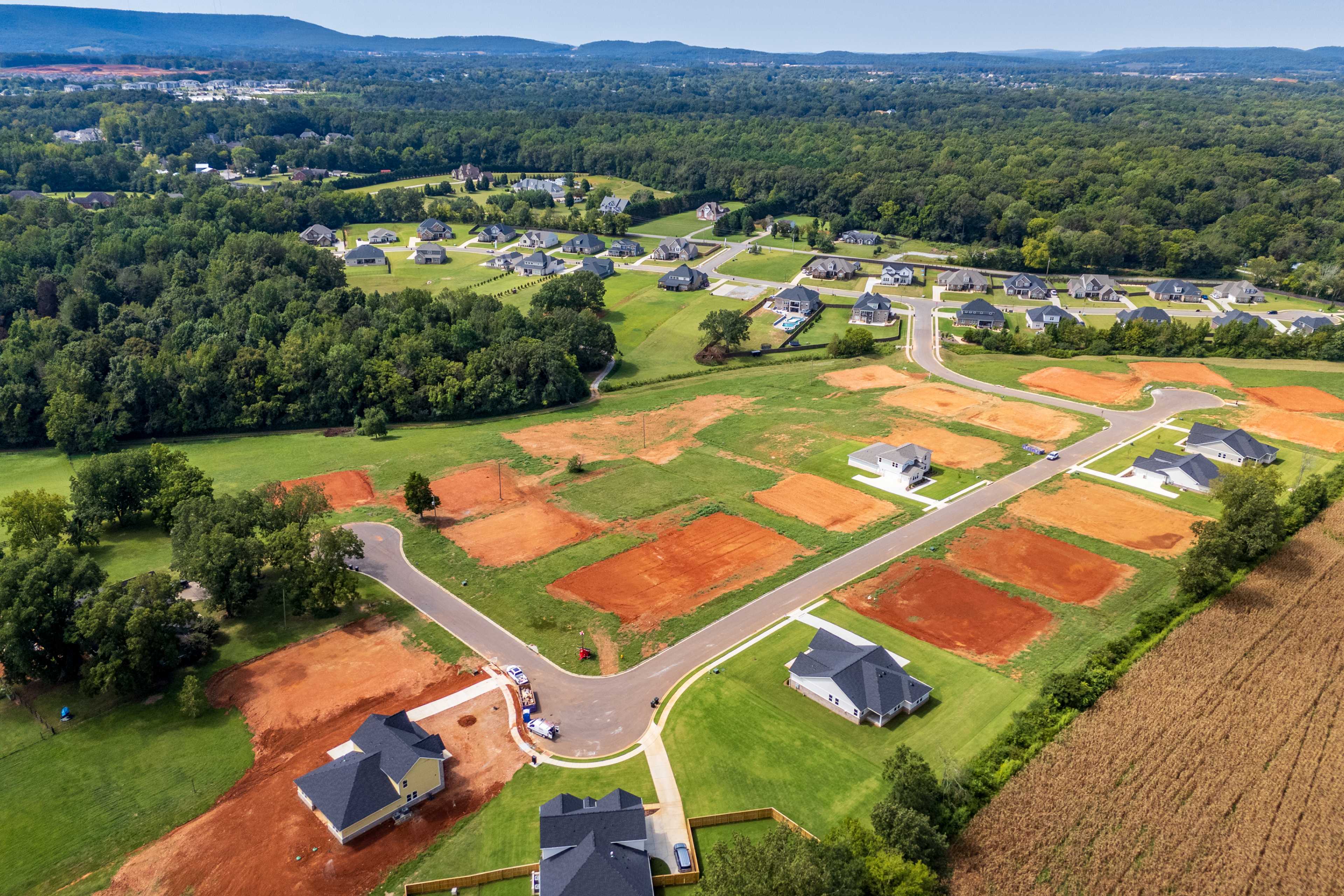 Aerial view of Riverton Preserve neighborhood in Huntsville Alabama with new homes construction sites red clay lots and wooded hills