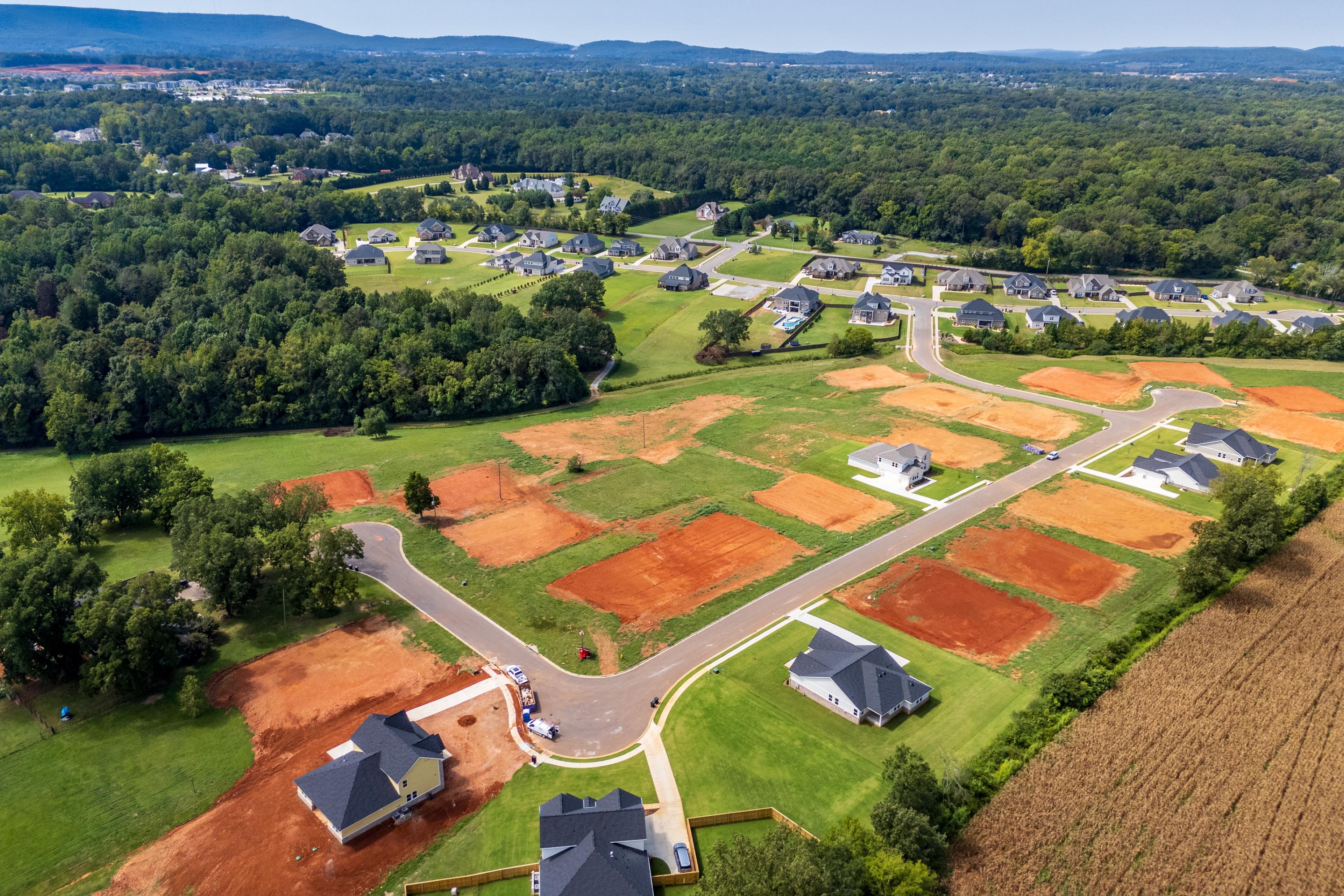 Aerial view of Riverton Preserve neighborhood in Huntsville Alabama with new homes construction sites red clay lots and wooded hills