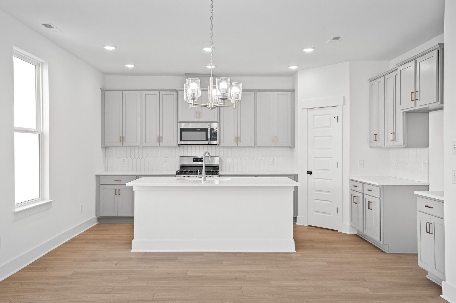 Bright modern kitchen with white quartz island, gray shaker cabinets, stainless appliances in Davidson Homes The Logan C, Gallatin TN