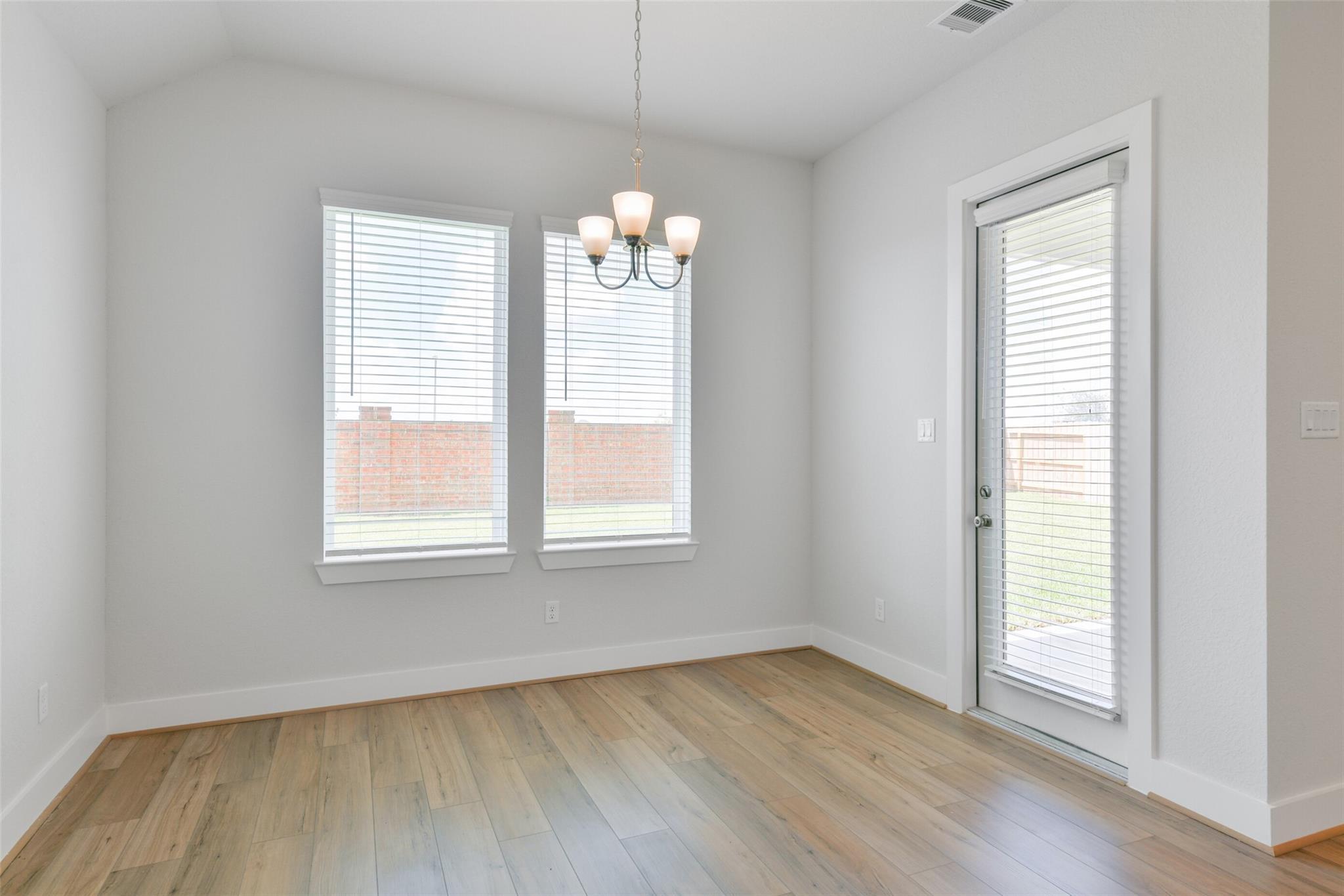 Bright dining room with hardwood floors, chandelier, large windows, and patio door in Davidson Homes The Edward A, Lago Mar, Texas City