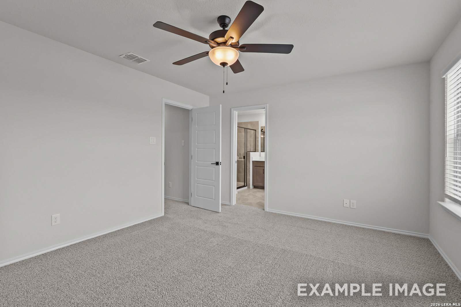 Spacious bedroom with ceiling fan and en-suite bathroom in The Florence D floor plan at Cedar Heights, San Antonio, Texas.