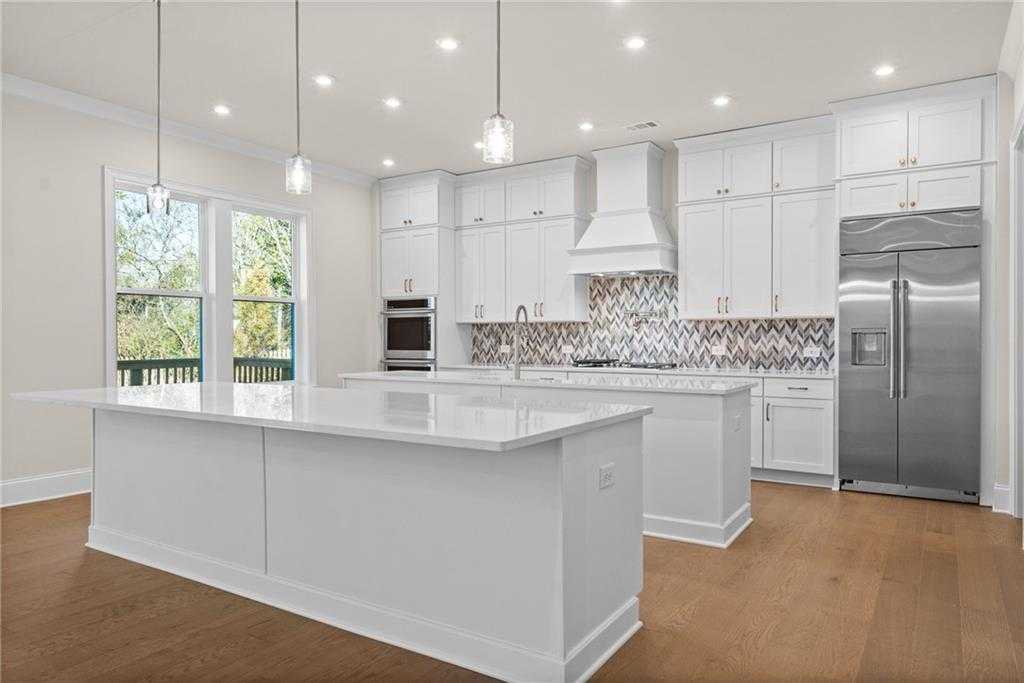 Modern white kitchen with quartz island, stainless fridge, range, and mosaic backsplash in Davidson Homes The Arlington A, East Cobb