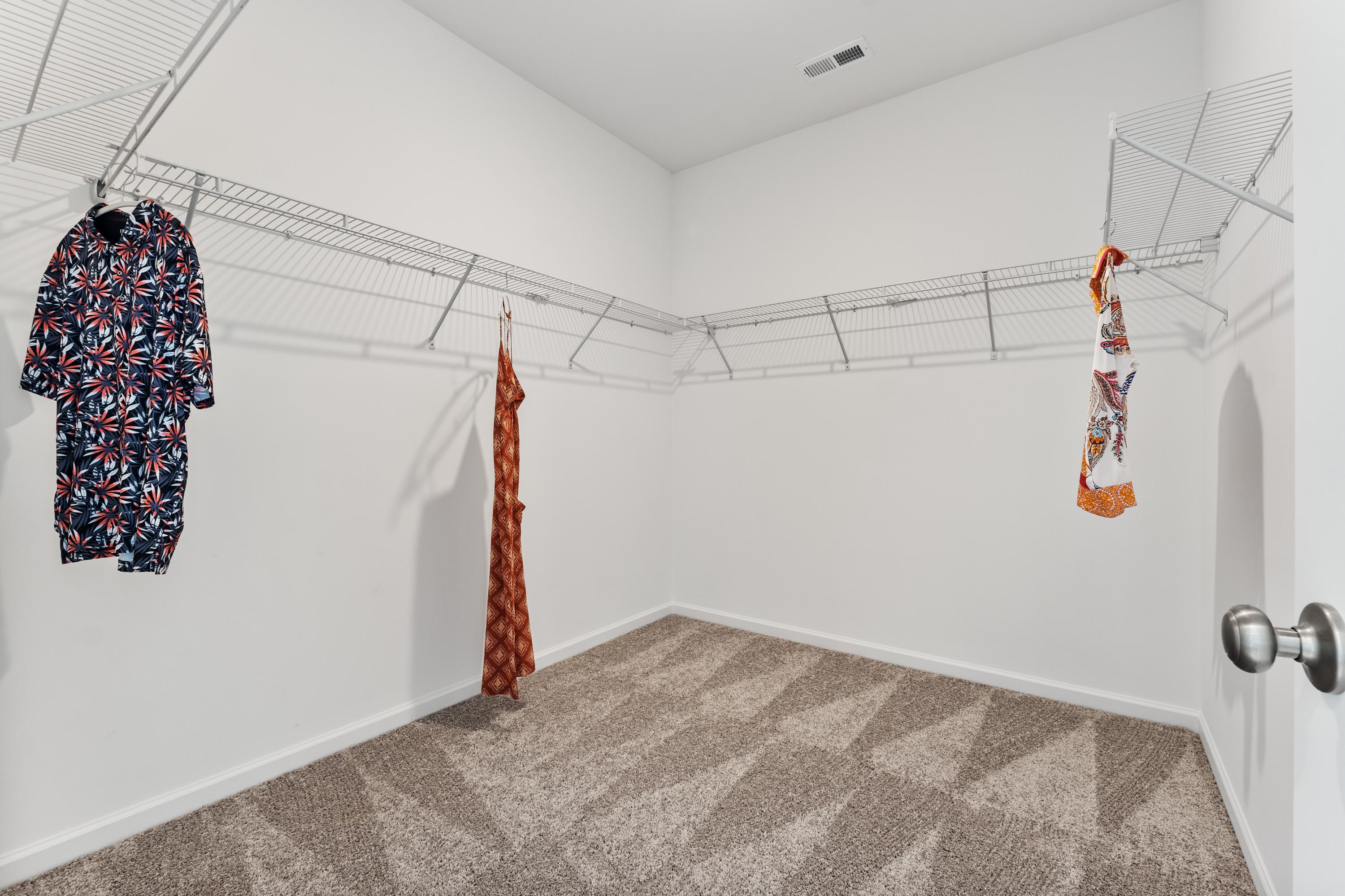 Spacious walk-in closet with wire shelving, hanging dresses and scarves at The Meadows at Hampton Cove, Owens Cross Roads AL
