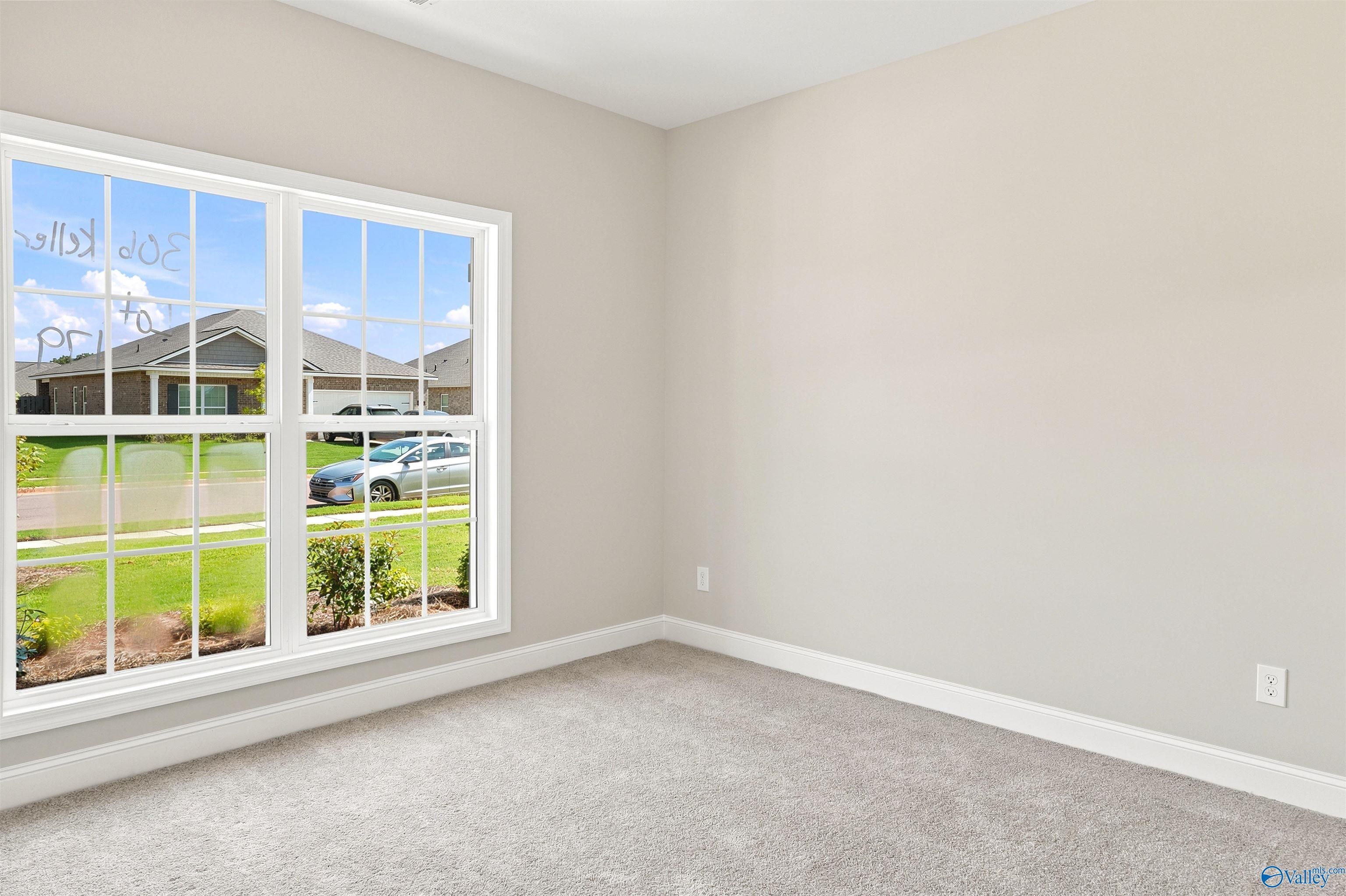 Bright bedroom with neutral carpet and large window in The Franklin B floor plan by Davidson Homes in Hazel Green, AL.