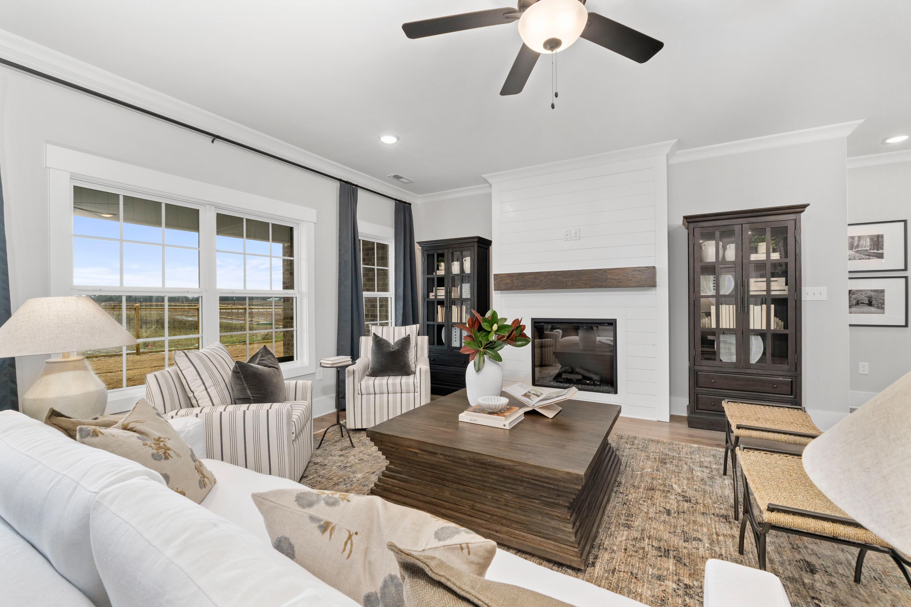 Spacious living room at Kendall Farms in Toney Alabama with shiplap fireplace, large field-view windows, and plush neutral seating