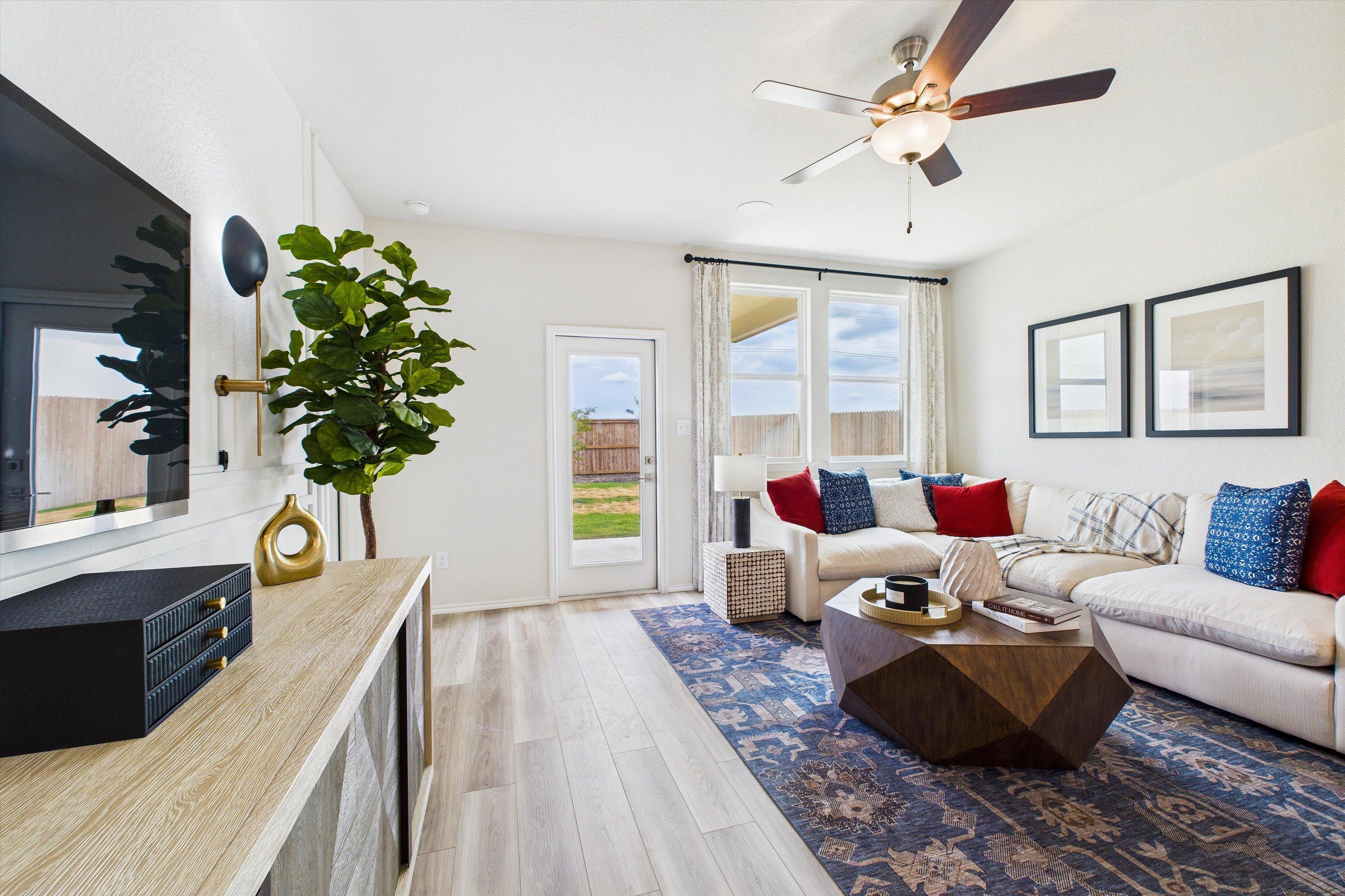 Spacious living room at Agave in San Antonio TX with beige L-shaped sofa, ceiling fan, mounted TV, and French doors to backyard
