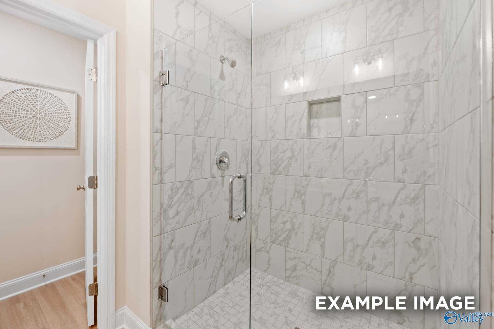 Frameless glass shower with white subway tiles, niche shelves, and modern fixtures in master bath of The Camden B by Davidson Homes, Huntsville