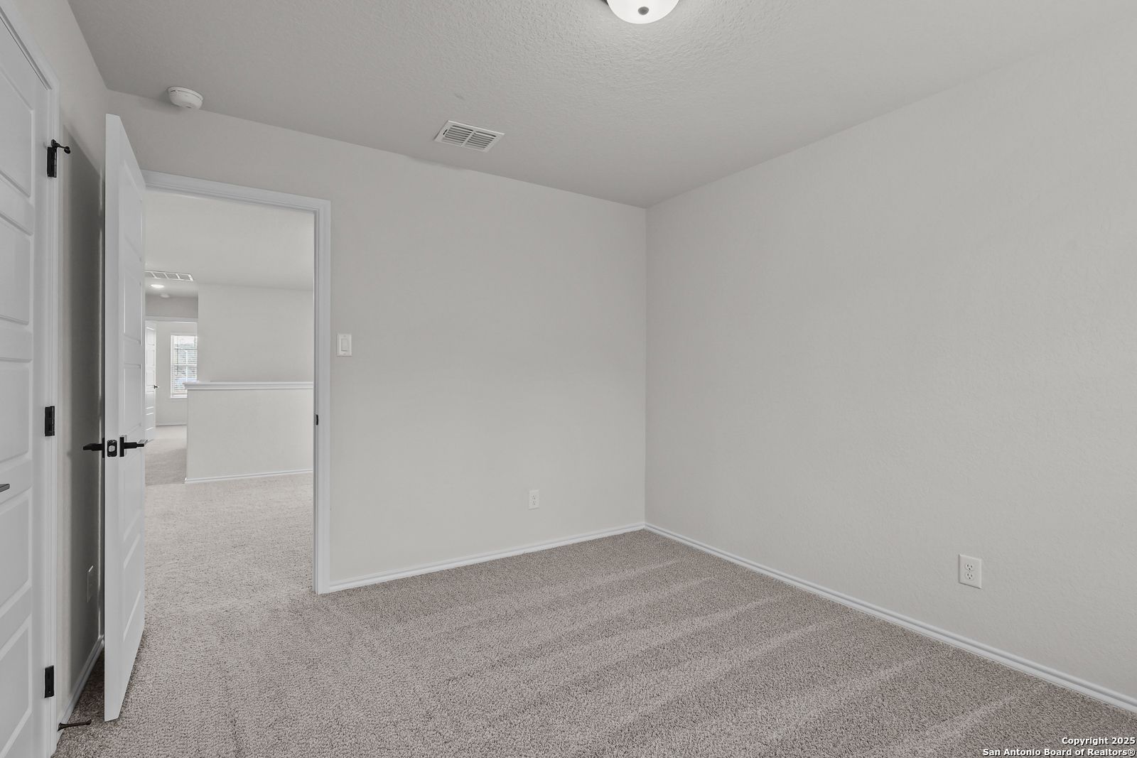 Spacious empty secondary bedroom with beige carpet and white walls in Davidson Homes The Florence C, San Antonio
