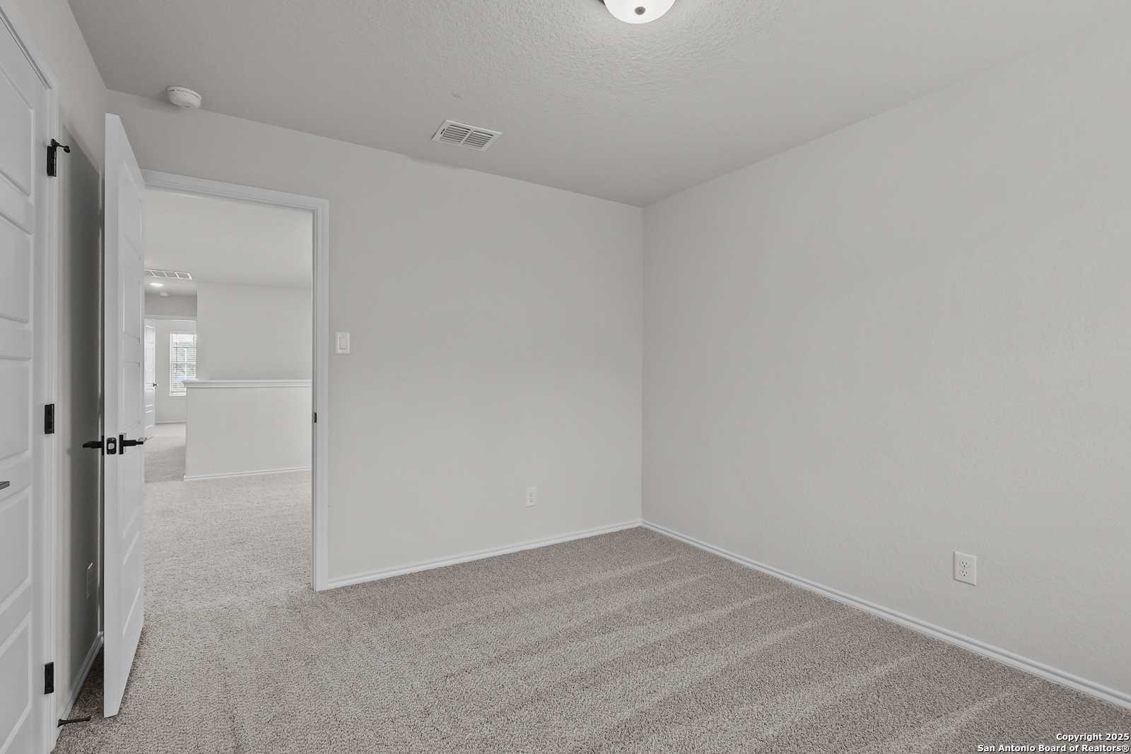 Spacious empty secondary bedroom with beige carpet and white walls in Davidson Homes The Florence C, San Antonio