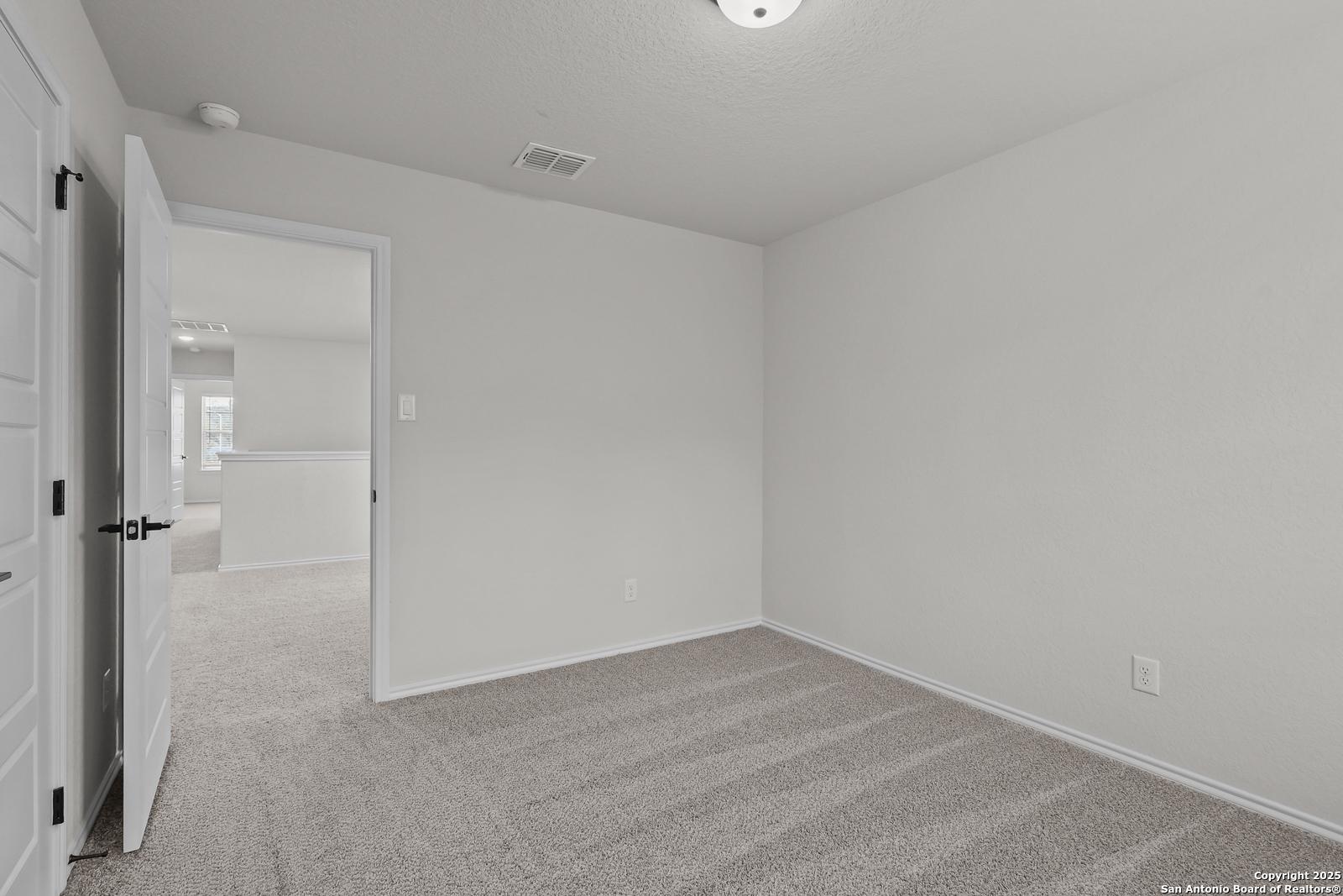 Spacious empty secondary bedroom with beige carpet and white walls in Davidson Homes The Florence C, San Antonio