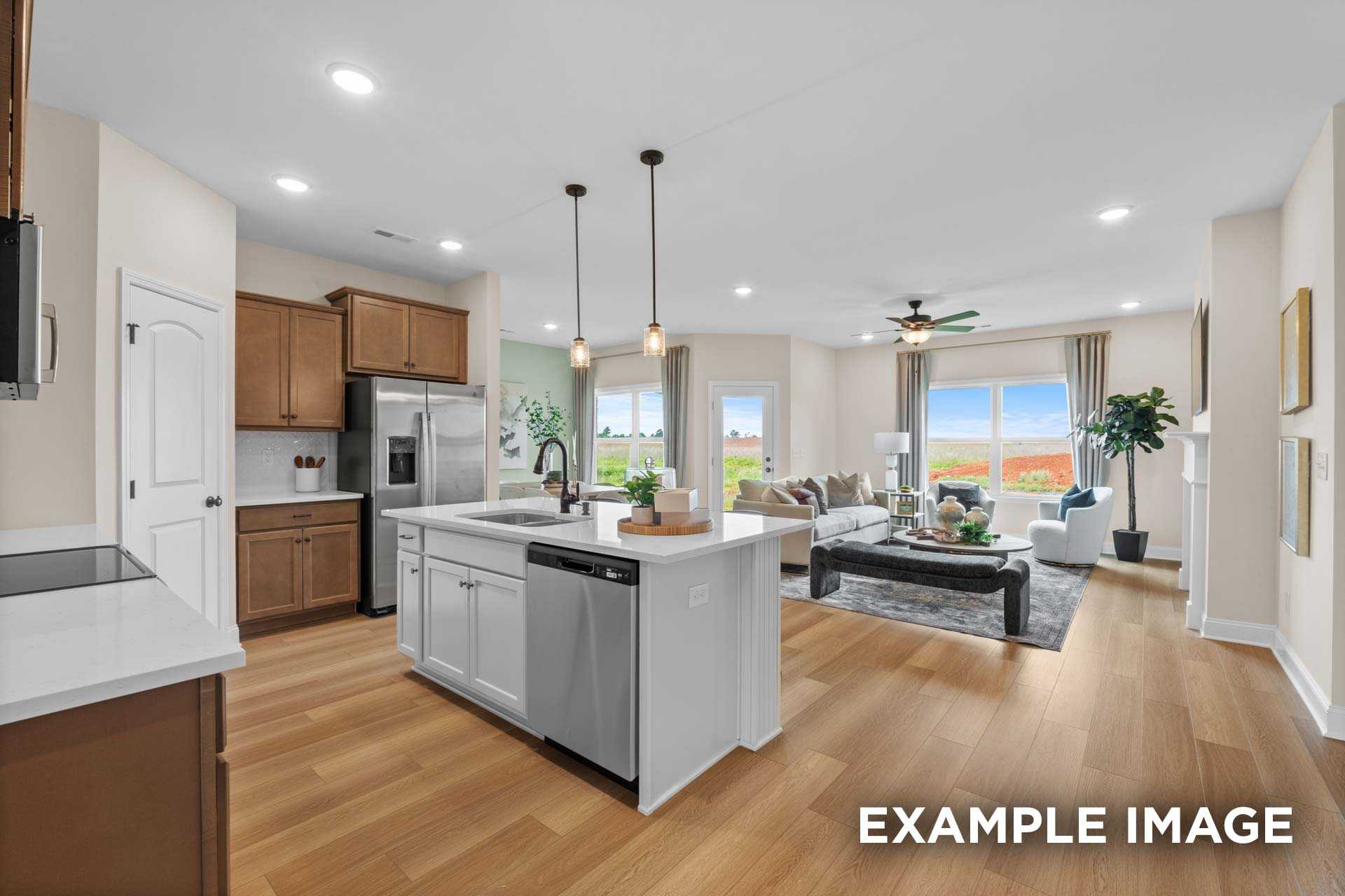 Open-concept kitchen and living room in The Laurel N with white island, stainless appliances, and cozy seating by Davidson Homes