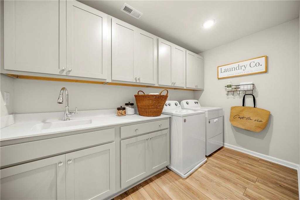 Spacious laundry room with white cabinets, utility sink, washer-dryer set in Davidson Homes The Hickory B, Dallas, Georgia