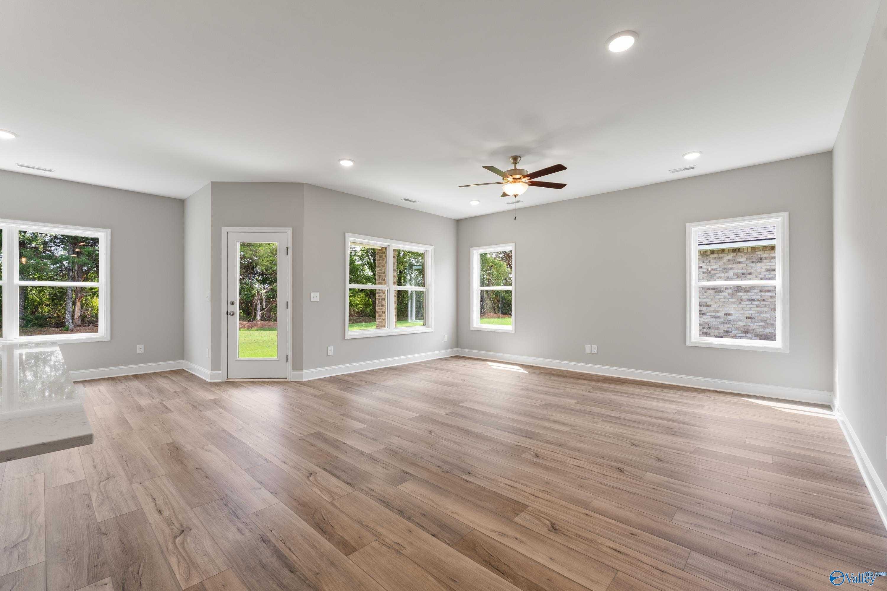 Spacious living room with hardwood floors, ceiling fan, large windows and French doors to green yard in Davidson Homes The Franklin C, Toney, AL