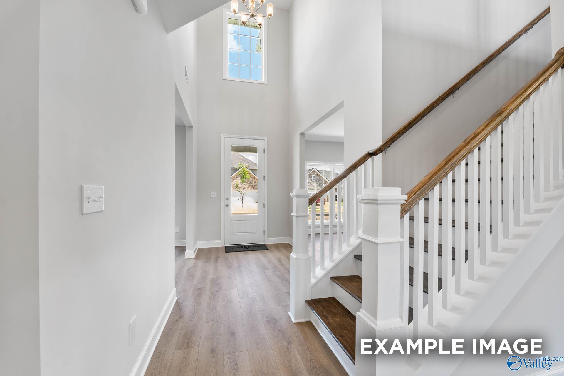 Grand two-story foyer with oak staircase, chandelier, and hardwood floors in Davidson Homes The Madison A, Meridianville, Alabama
