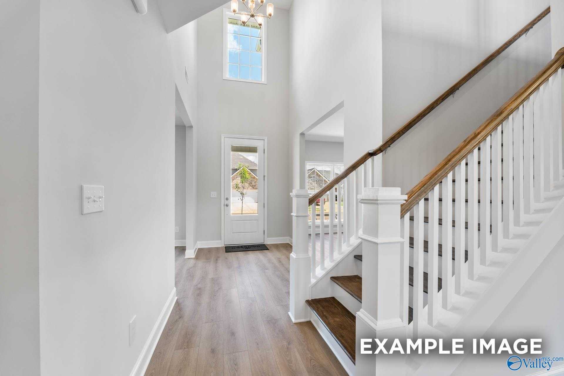 Grand entry foyer with curved wooden staircase, chandelier, and high ceilings in Davidson Homes The Madison A, Meridianville, Alabama