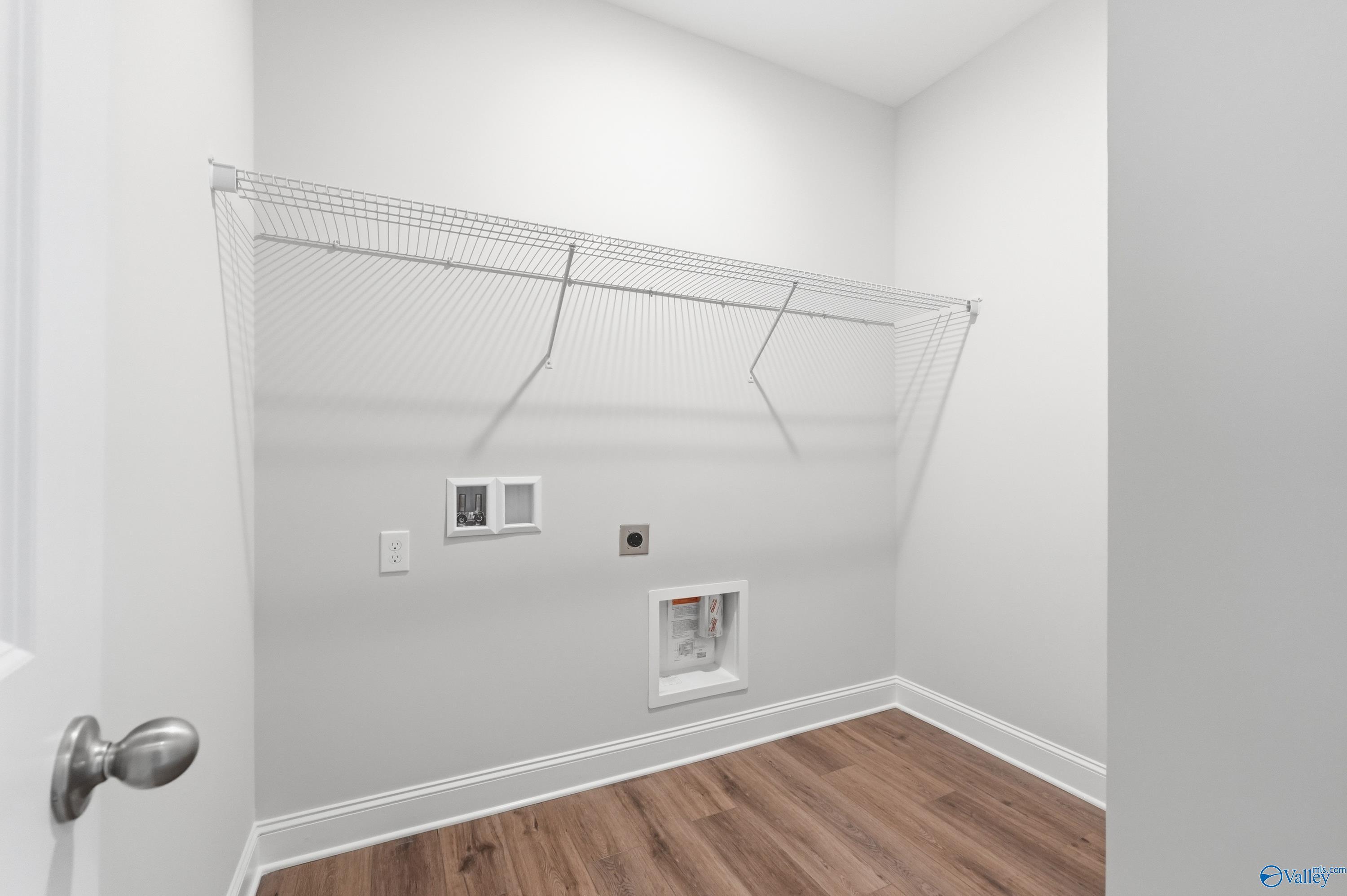 Bright laundry room with wire shelving, utility hookups and hardwood floors in Davidson Homes The Daphne C, Toney, Alabama