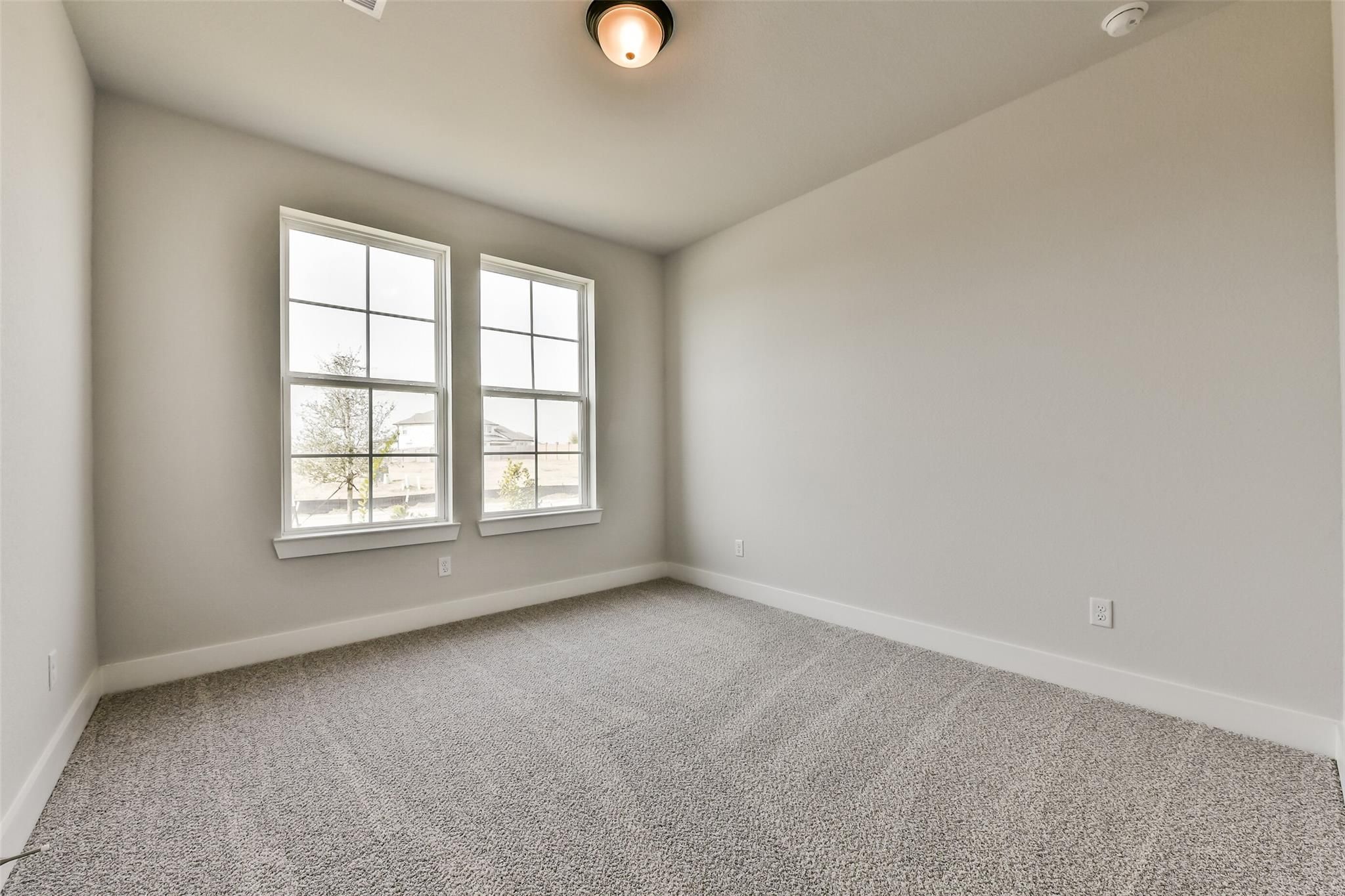 Bright empty bedroom with beige carpet, light gray walls, and double windows in Davidson Homes The George A, Lago Mar, Texas City