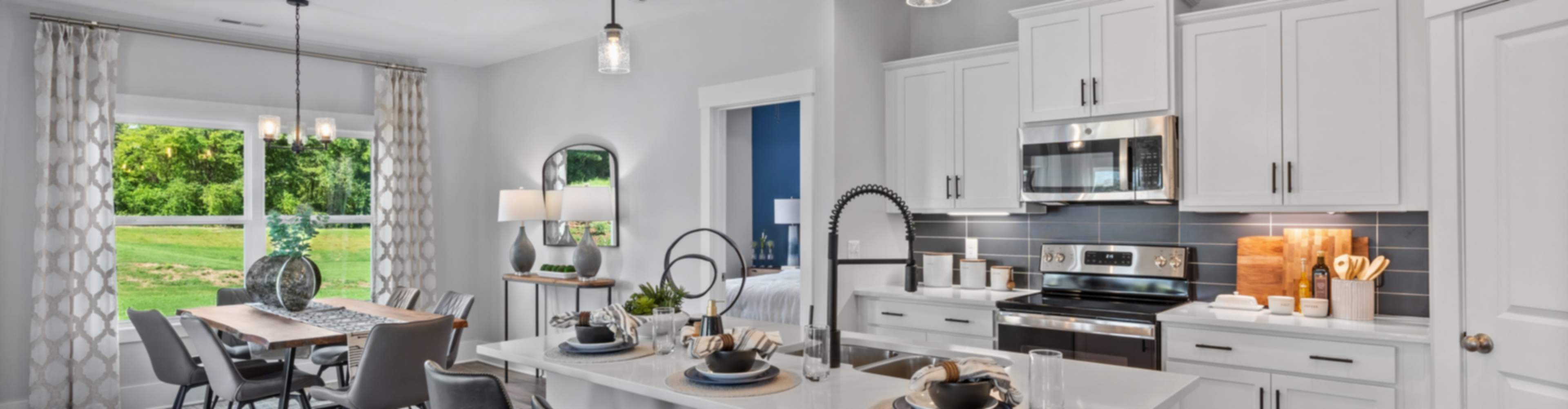 Spacious modern kitchen in new Arab home with white cabinets, large island, bar stools, and dining nook overlooking greenery