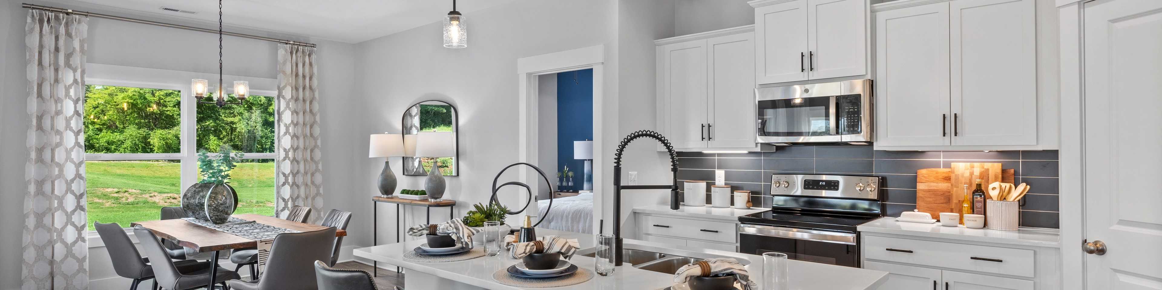 Spacious modern kitchen in new Arab home with white cabinets, large island, bar stools, and dining nook overlooking greenery