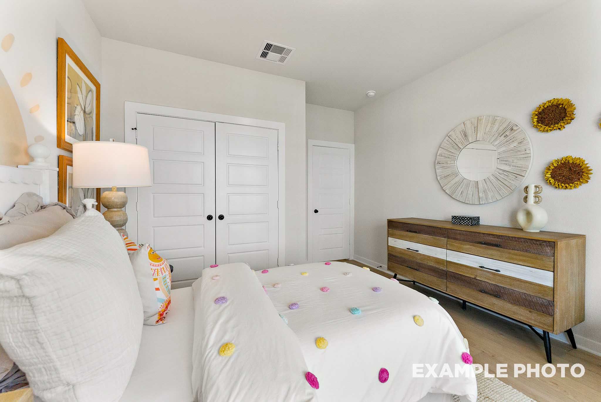Cozy secondary bedroom with decorative pom-pom bedding in The Everett E floor plan by Davidson Homes in Crosby, Texas.