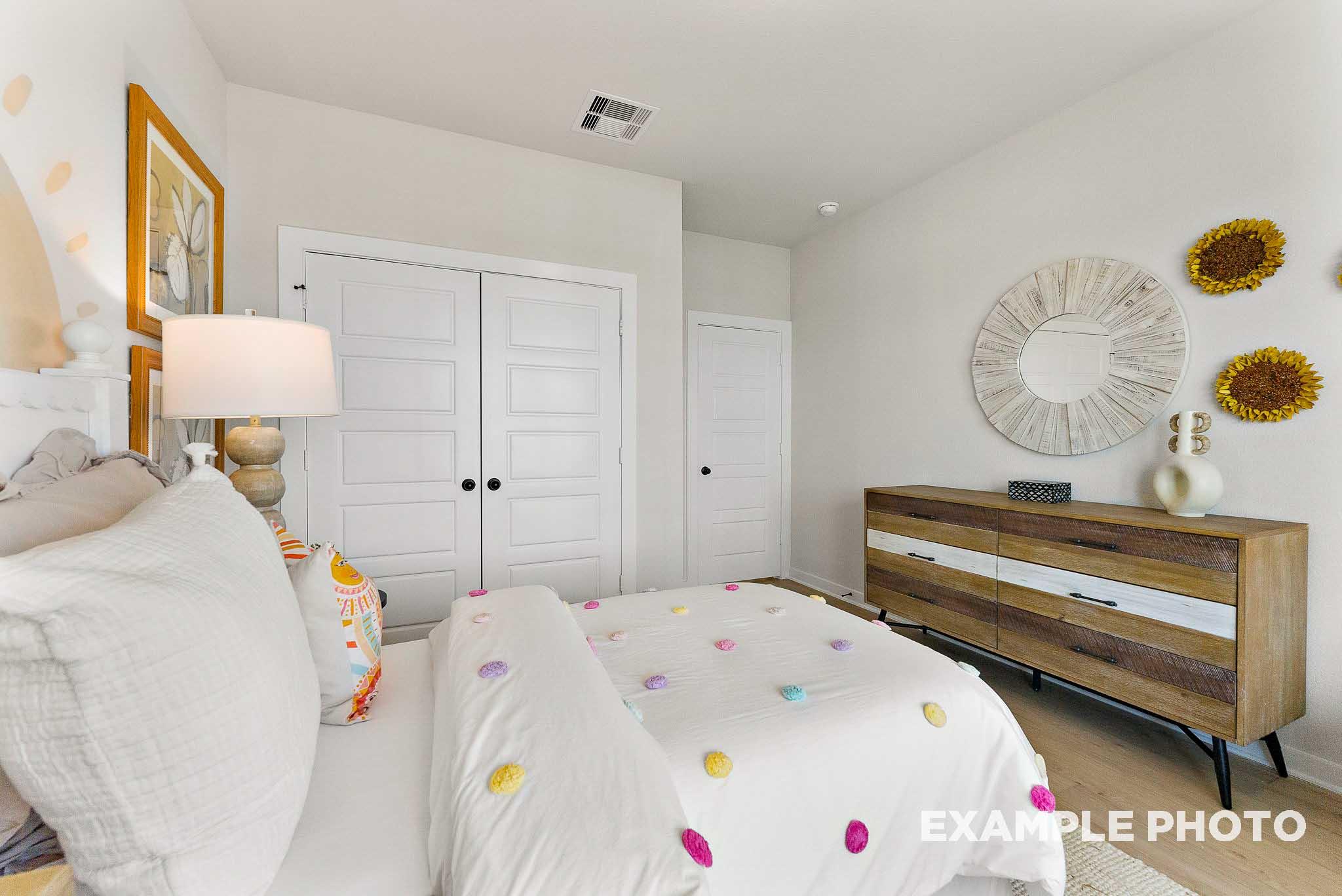 Cozy secondary bedroom with decorative pom-pom bedding in The Everett E floor plan by Davidson Homes in Crosby, Texas.
