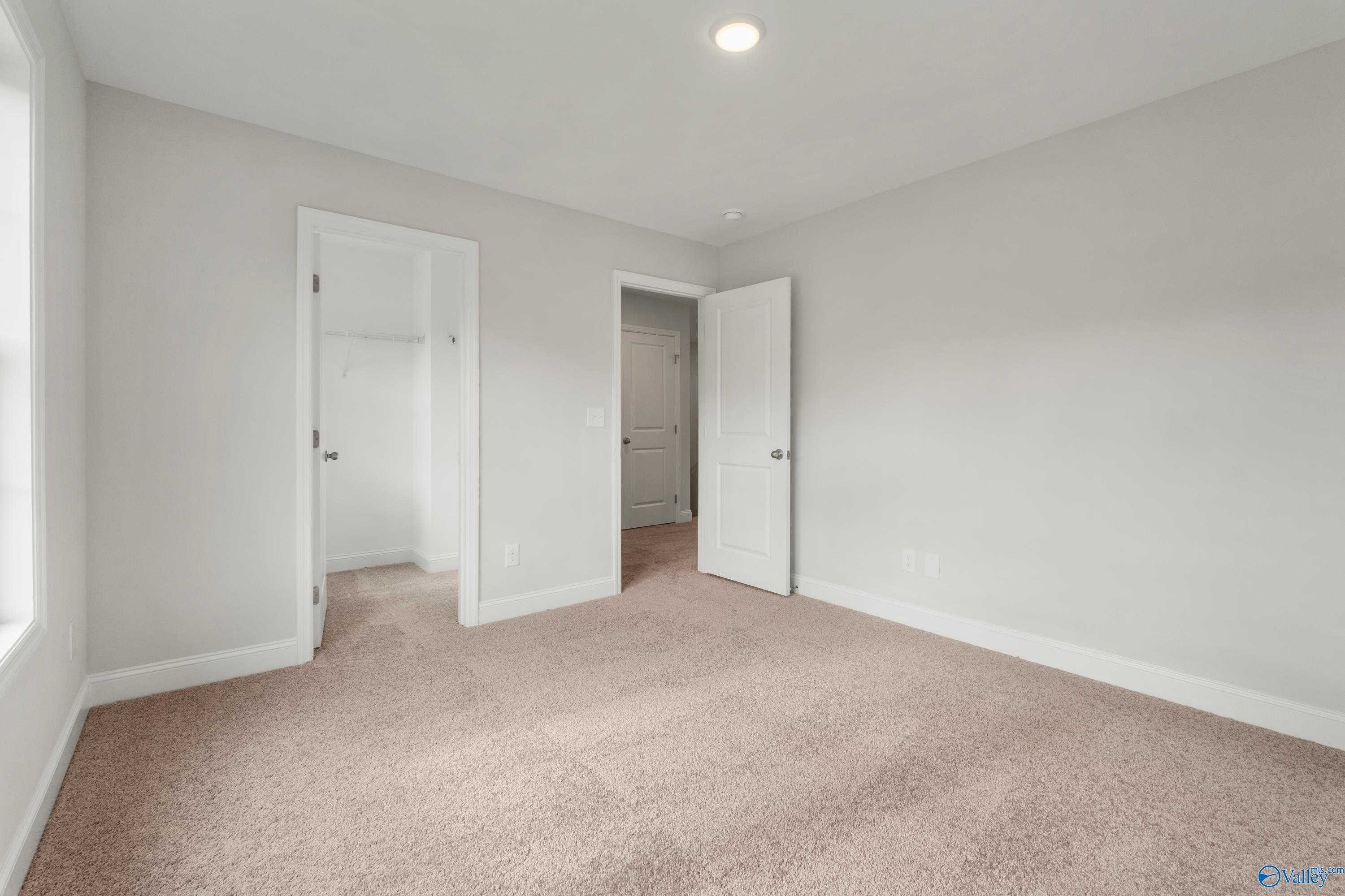 Bright secondary bedroom with open closet and bath doors, beige carpet in Davidson Homes Chelsea C, Harvest, Alabama