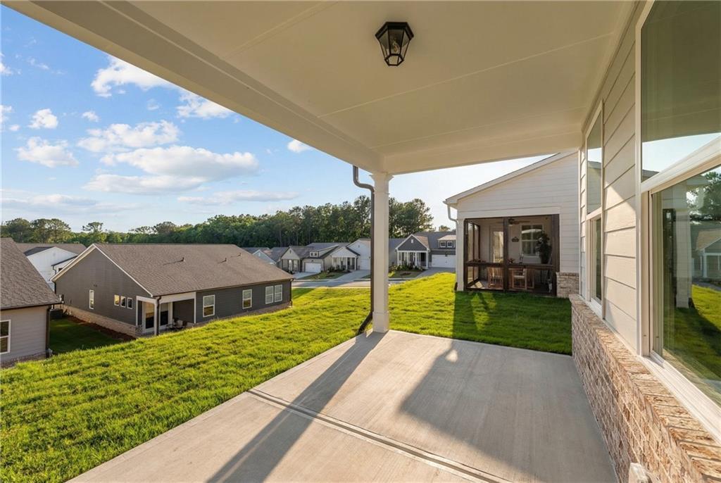 Covered front porch with white columns, lantern light, and screen door overlooking lush green lawn and neighborhood homes in Kelly Preserve, Loganville, Georgia