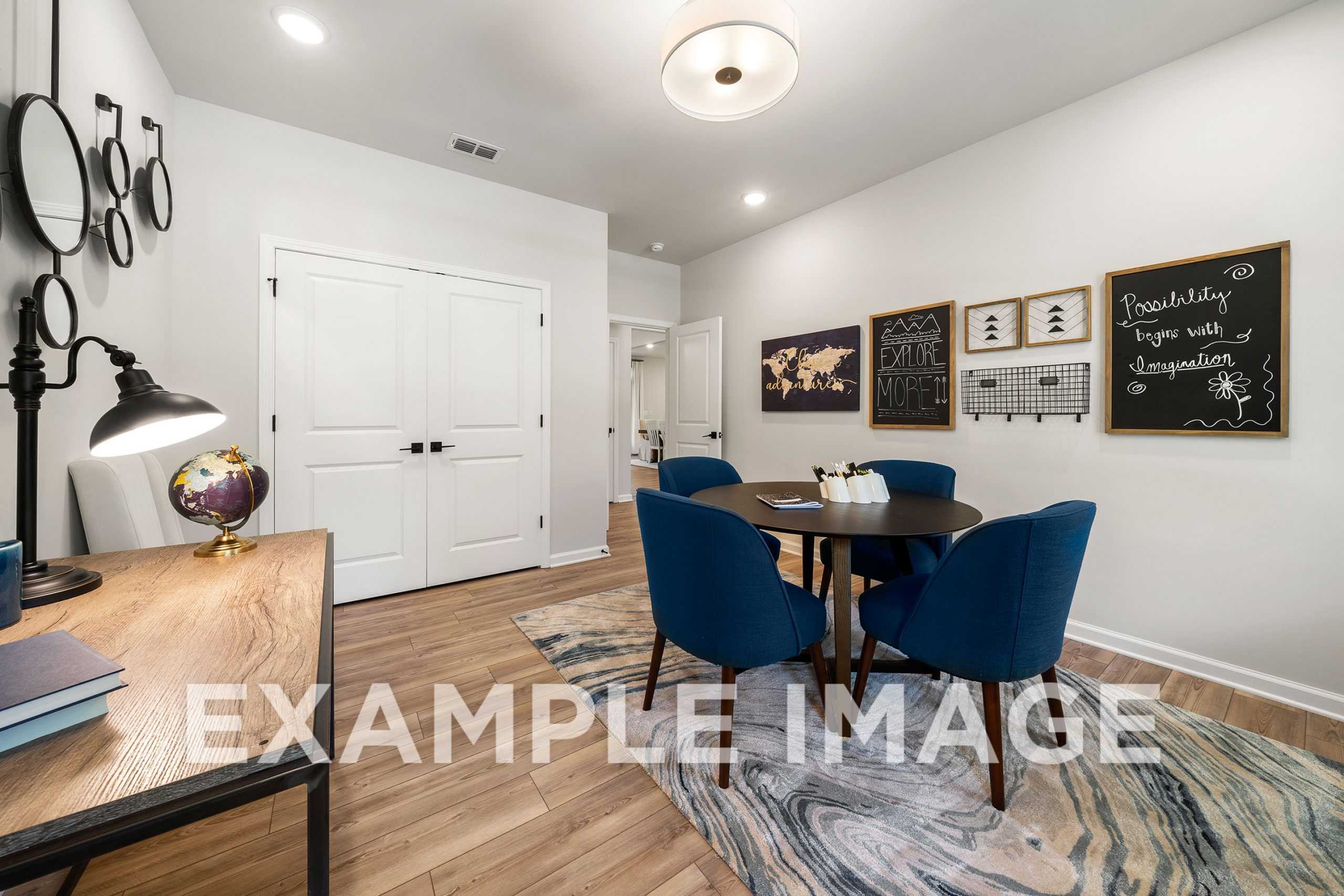 Cozy study room in The Hickory A with wooden desk, blue velvet chairs at round table, world map, and chalkboard accents