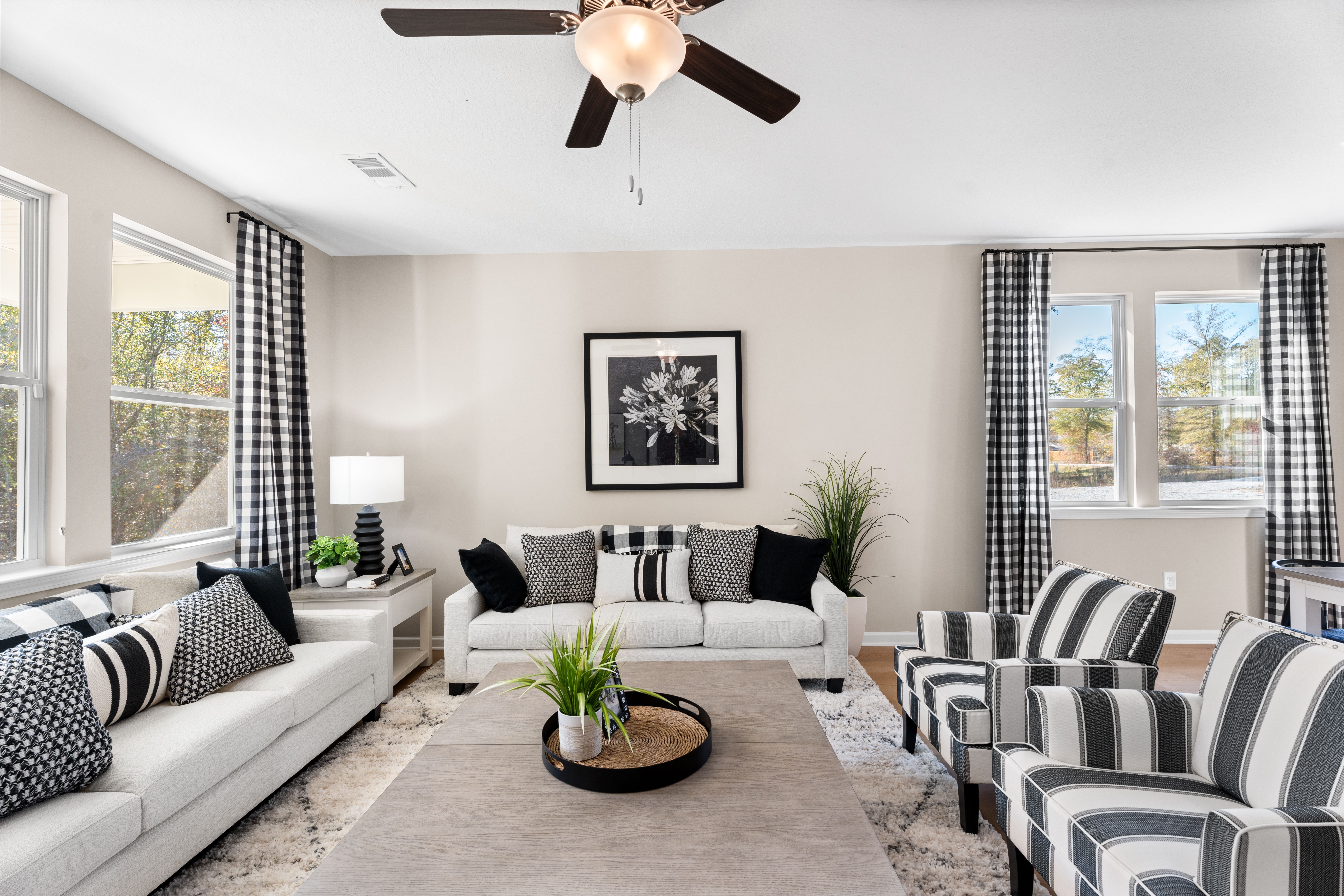 Open-concept living room at Silver Oak in Cusseta Alabama with neutral tones hardwood floors white sofa blue armchairs and potted plants