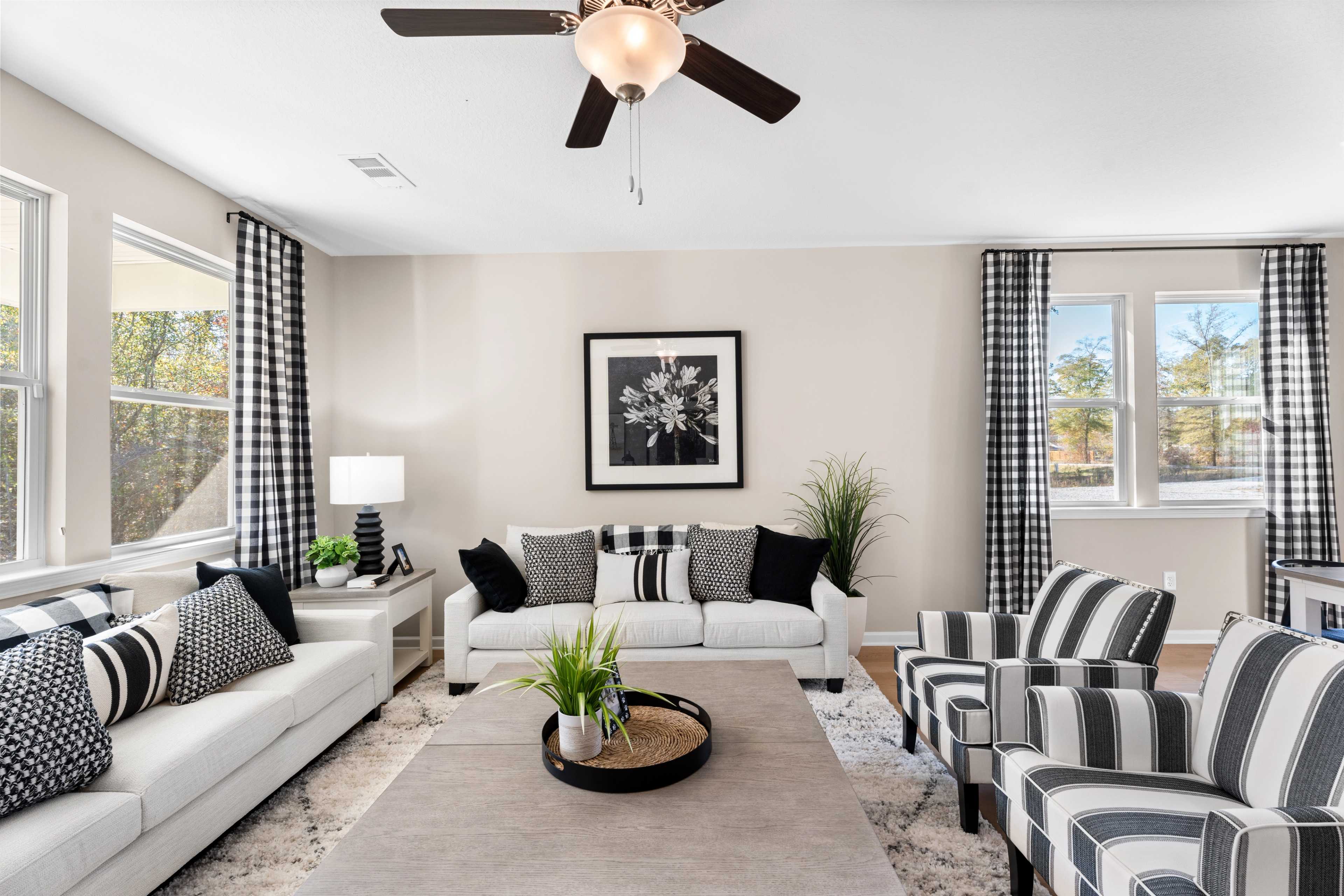 Open-concept living room at Silver Oak in Cusseta Alabama with neutral tones hardwood floors white sofa blue armchairs and potted plants