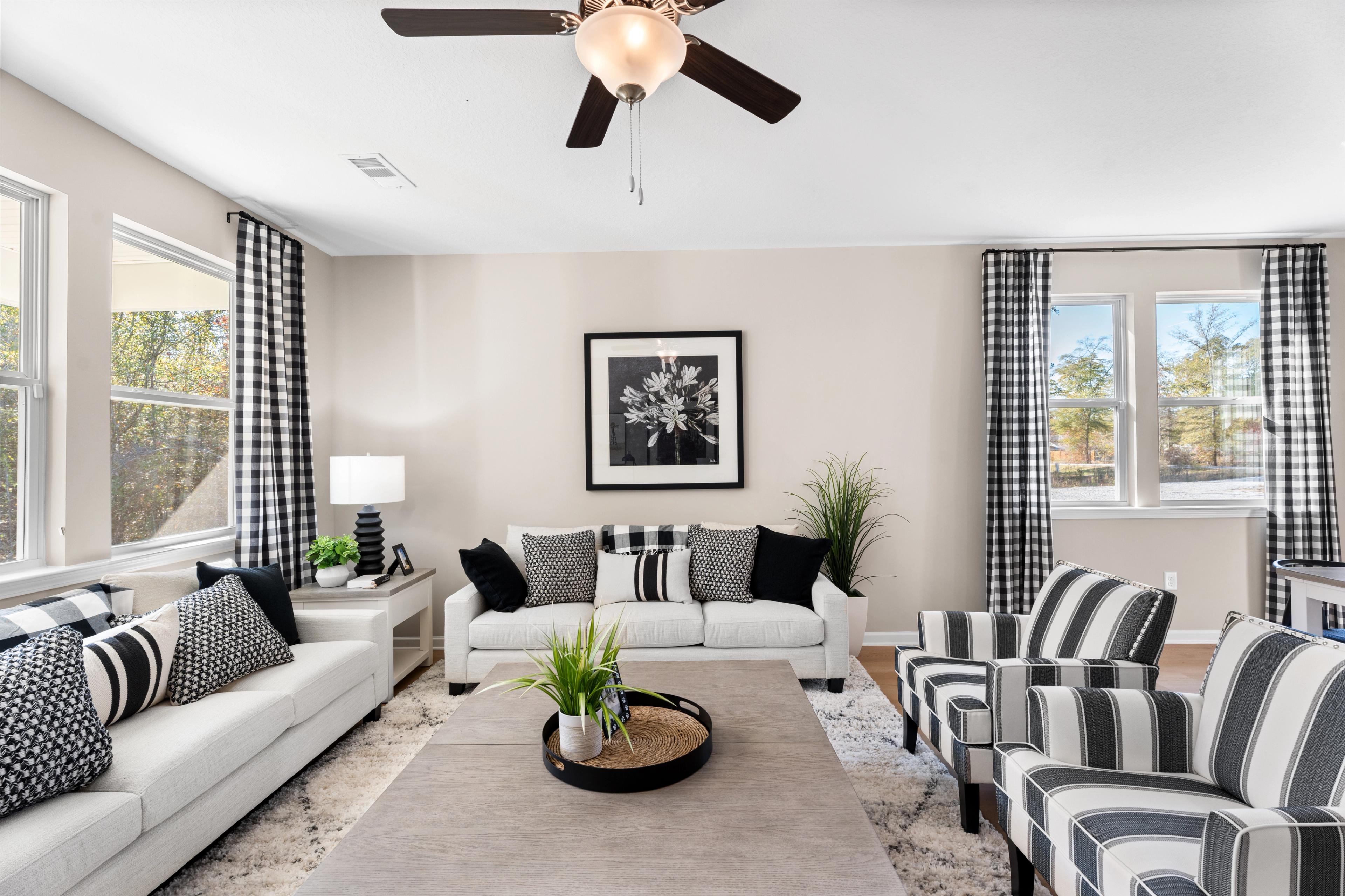 Open-concept living room at Silver Oak in Cusseta Alabama with neutral tones hardwood floors white sofa blue armchairs and potted plants