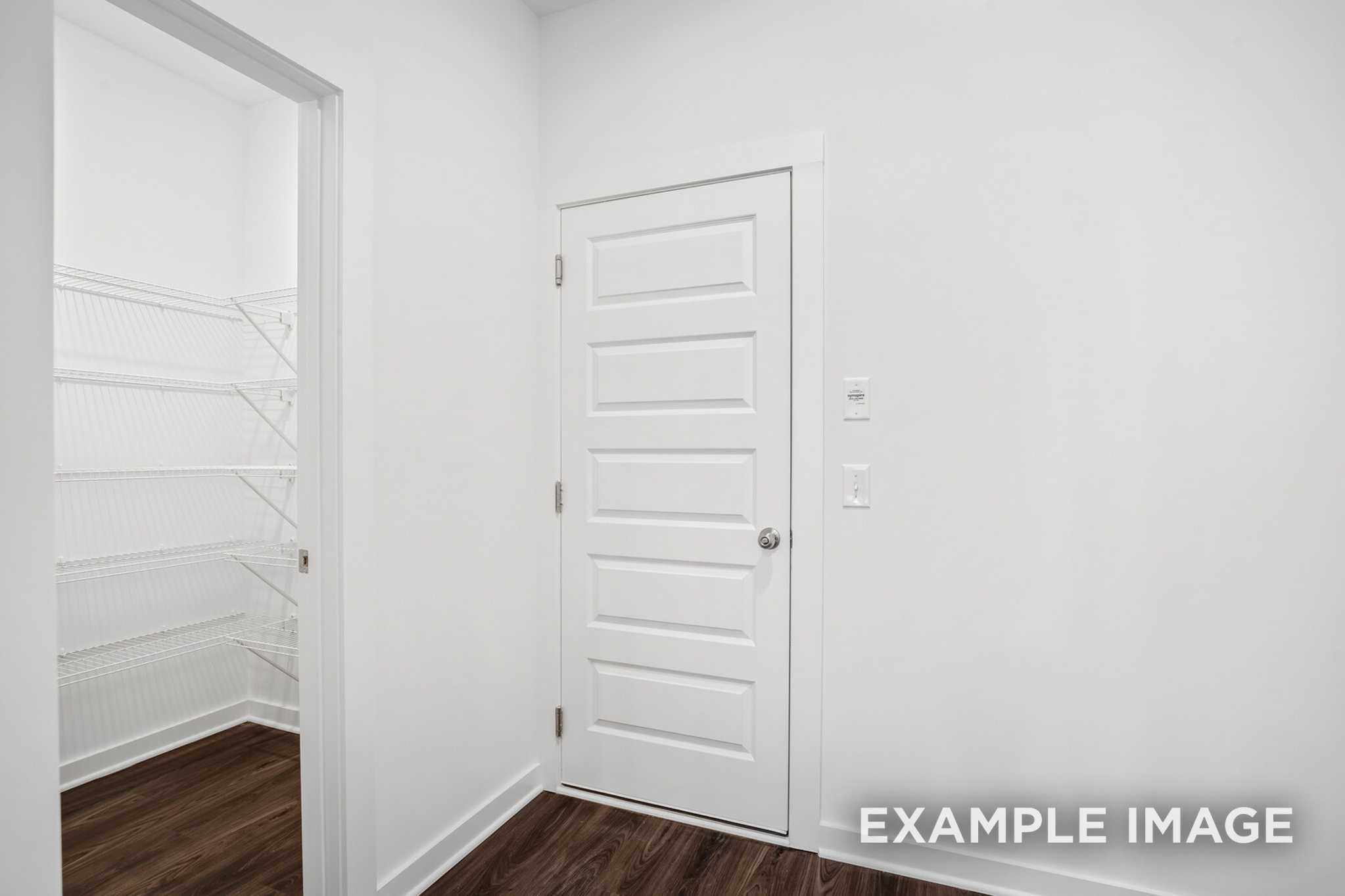 Spacious master closet in The Grayson C with white wire shelving, hanging rod, paneled door, and hardwood floors