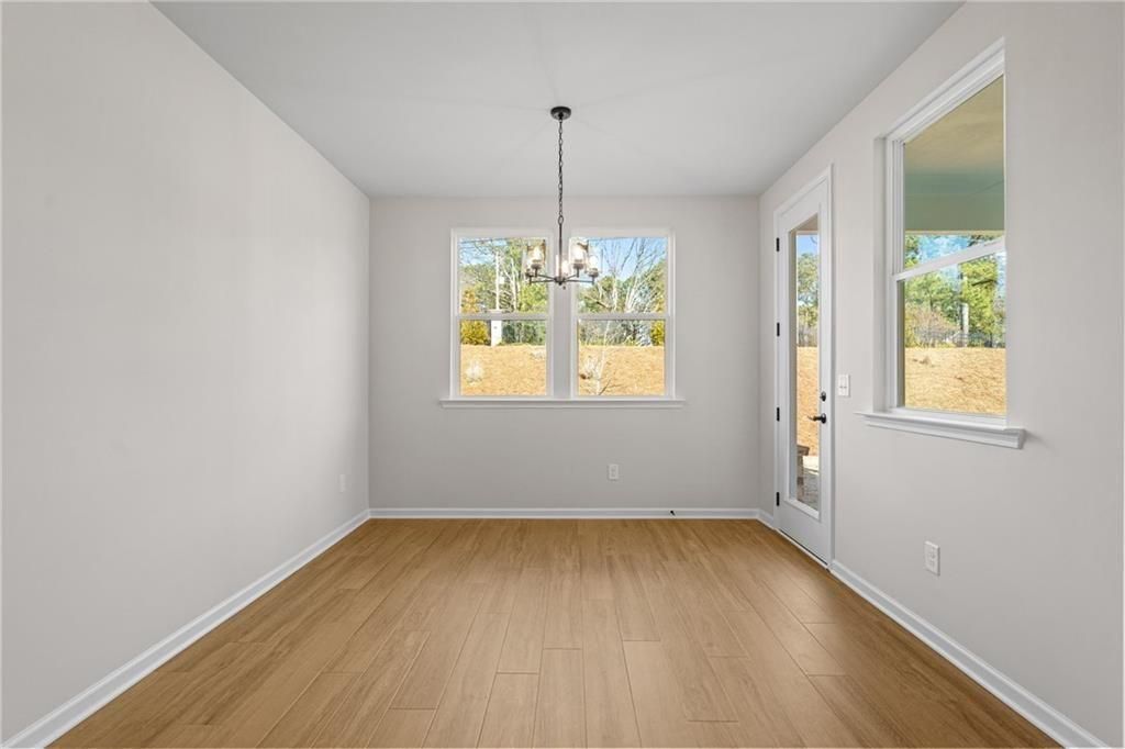 Bright dining room with hardwood floors, modern chandelier, large windows, and glass door in Davidson Homes The Edison A, Loganville, GA
