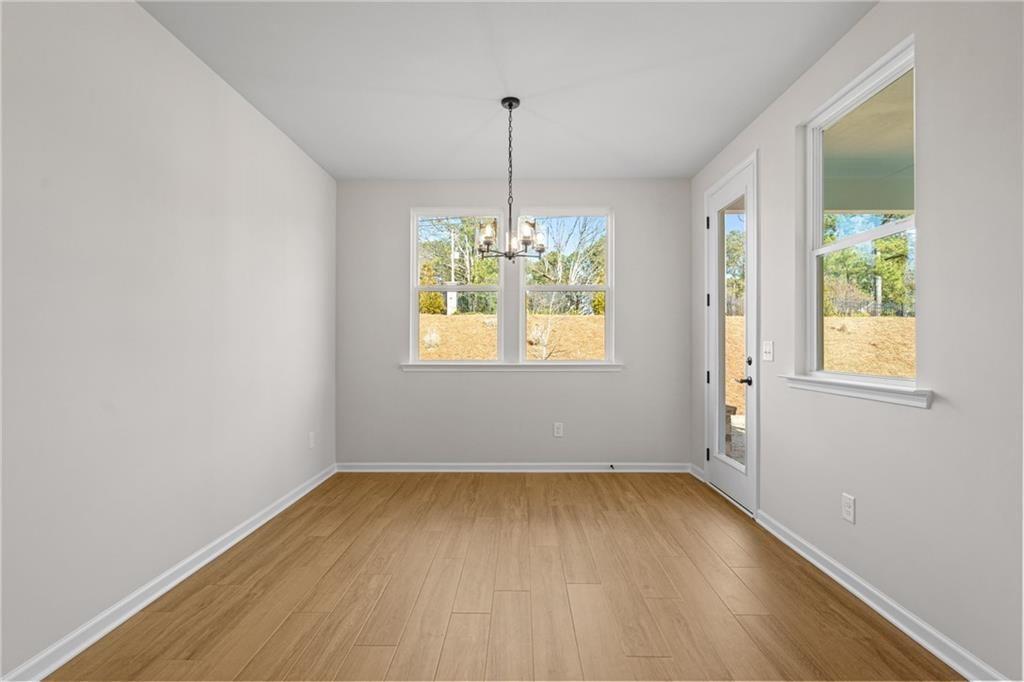 Bright dining room with hardwood floors, modern chandelier, large windows, and glass door in Davidson Homes The Edison A, Loganville, GA