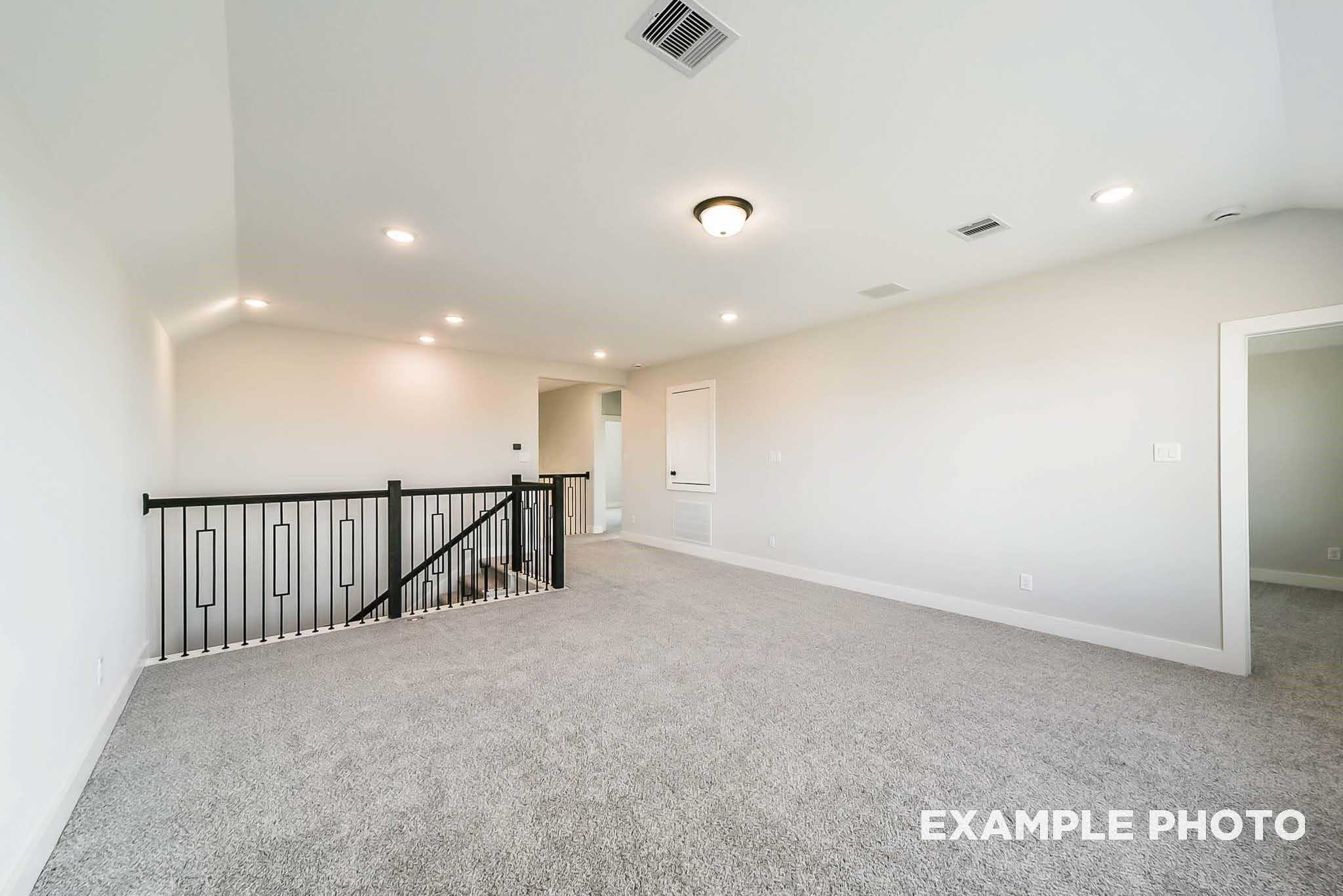 Spacious upstairs loft with black metal railing, carpeted floors, and recessed lighting in 4-bedroom Davidson Homes The Philip C, Rosharon, Texas