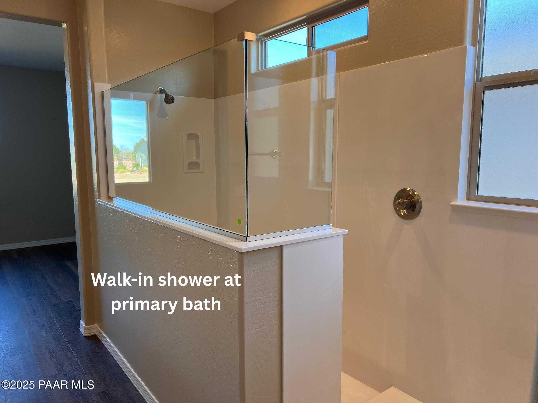 Modern walk-in shower with frameless glass enclosure and beige tile in primary bath, Davidson Homes The Inspiration A, Prescott Valley