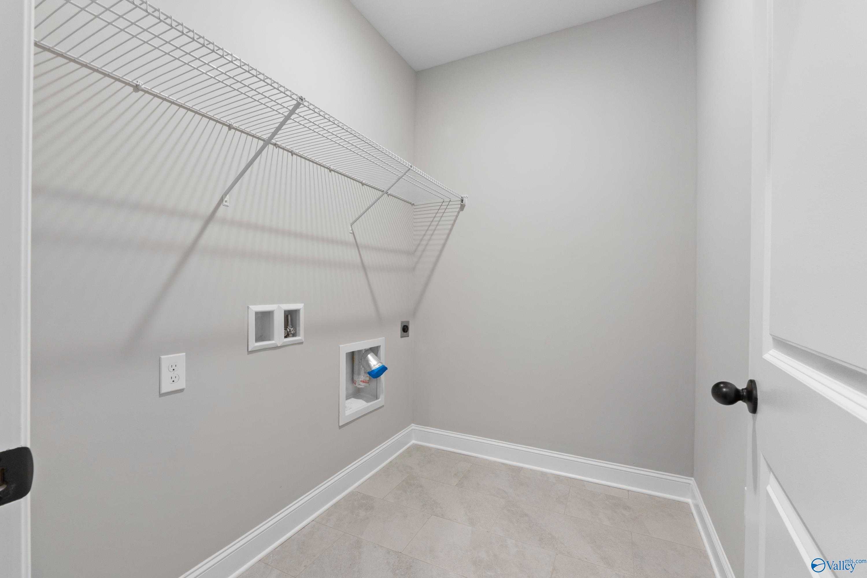 Well-organized laundry room with wire shelving, washer dryer hookups, and gray walls in Davidson Homes The Rockford with Bonus, Toney, Alabama