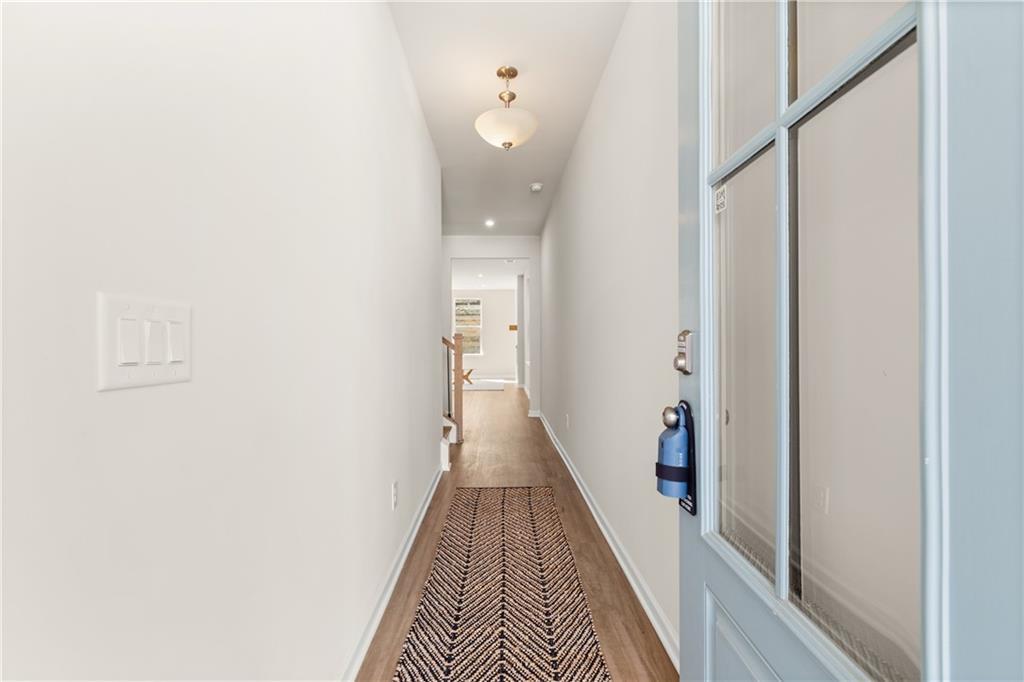 Bright hallway with white walls, hardwood floors, patterned rug, and blue glass front door in Davidson Homes The Marion B, Kennesaw, GA