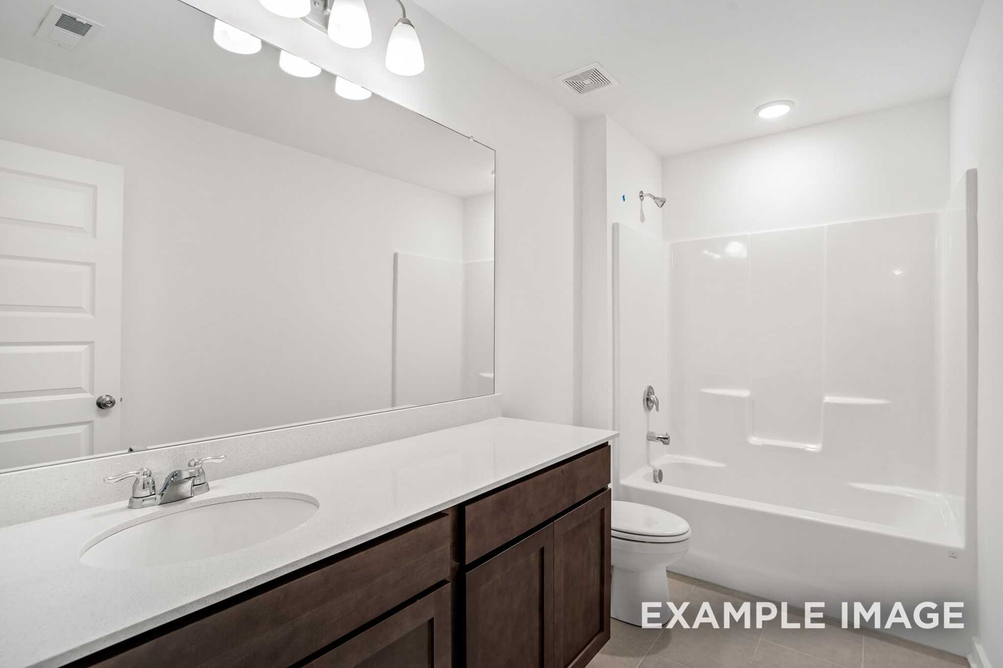 Spacious master bathroom in The Grayson C with double vanity, soaking tub, walk-in shower, and large mirror