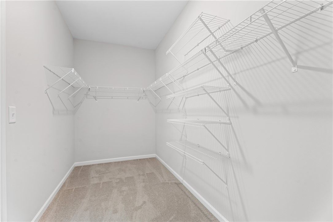 Spacious walk-in closet with white wire shelving and hanging rods in Davidson Homes The Luna B, Opelika, Alabama
