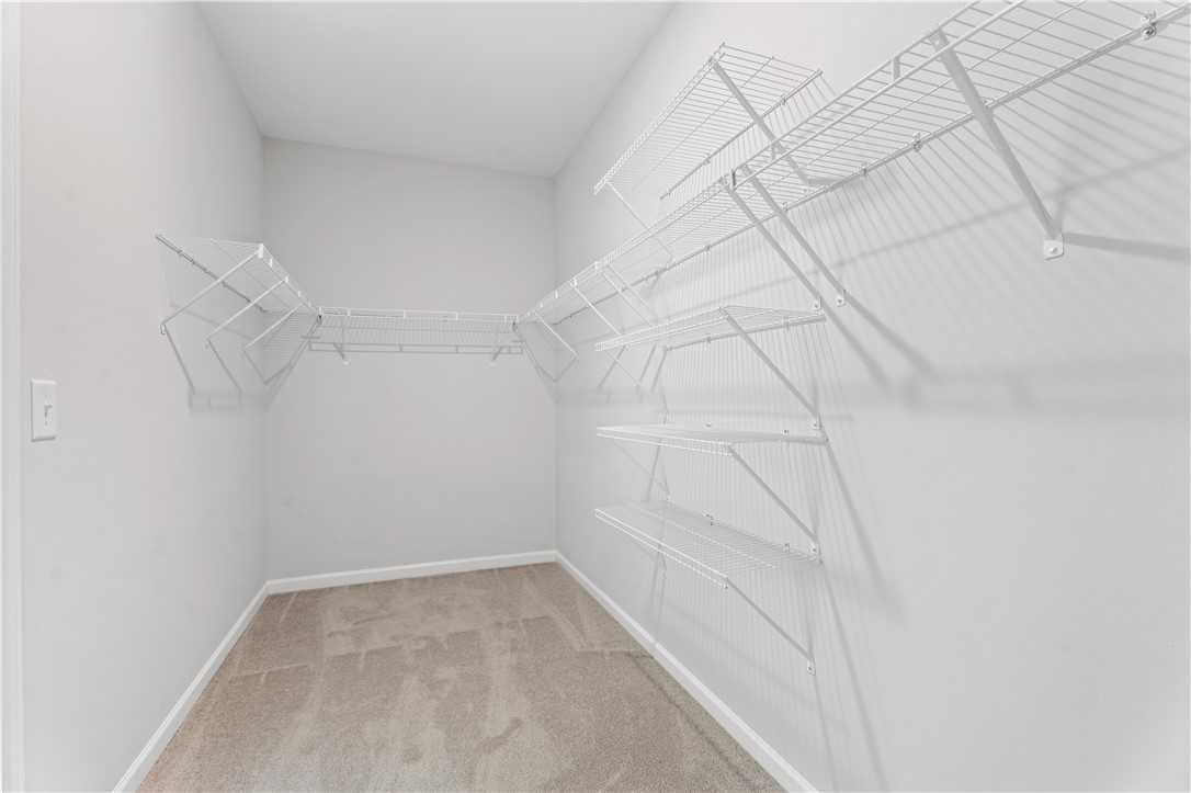 Spacious walk-in closet with white wire shelving and hanging rods in Davidson Homes The Luna B, Opelika, Alabama