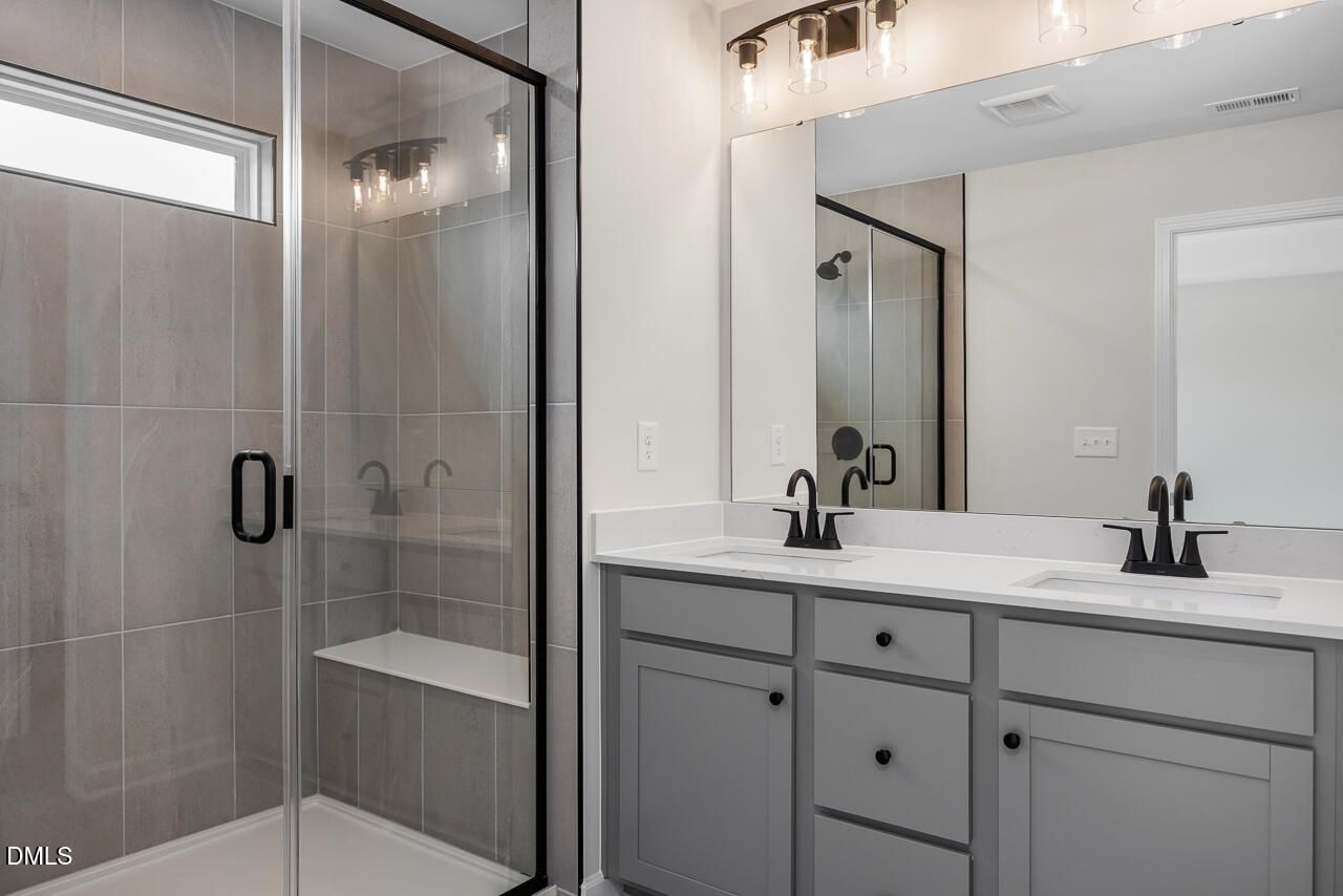 Modern bathroom with glass-enclosed shower and dual-sink vanity in The Mitchell Interior at Forestville Yard, Knightdale.