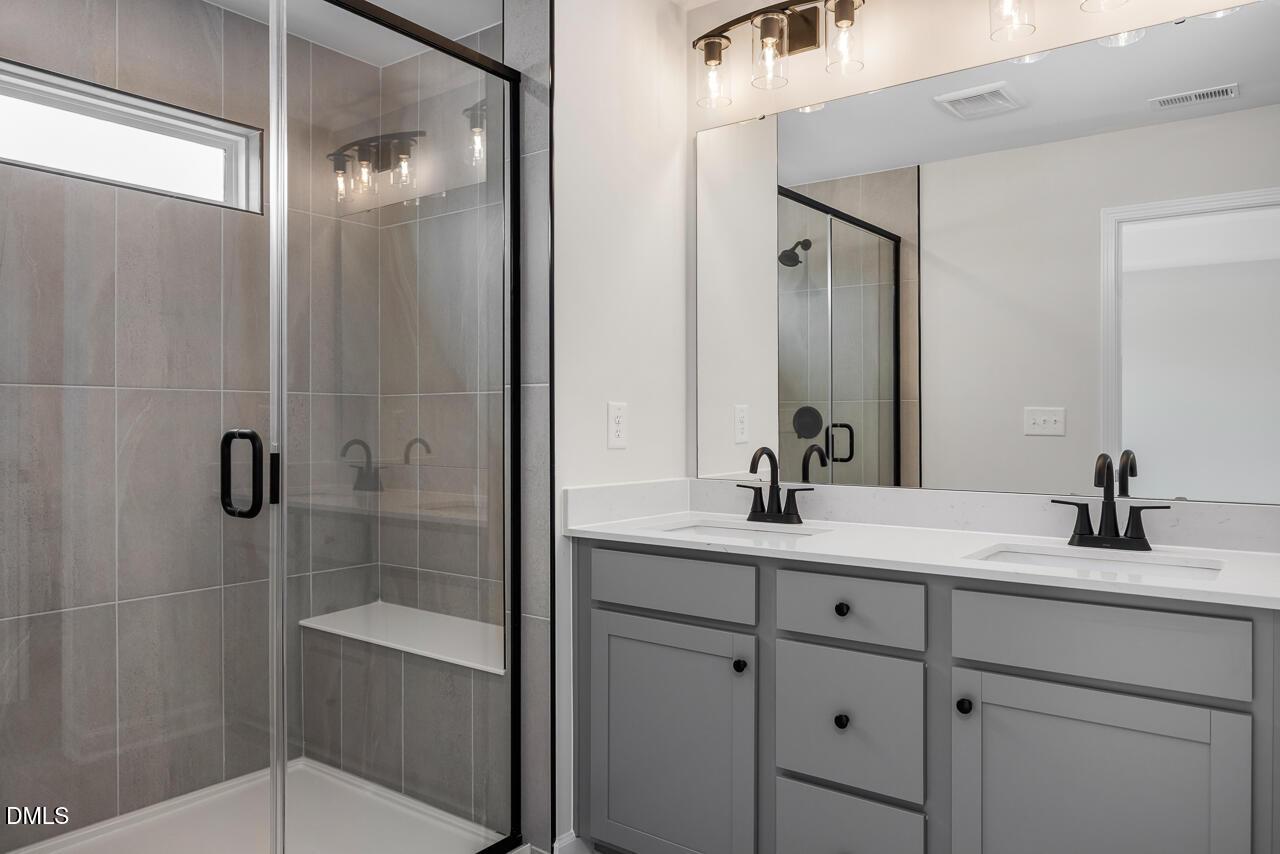 Modern bathroom with glass-enclosed shower and dual-sink vanity in The Mitchell Interior at Forestville Yard, Knightdale.