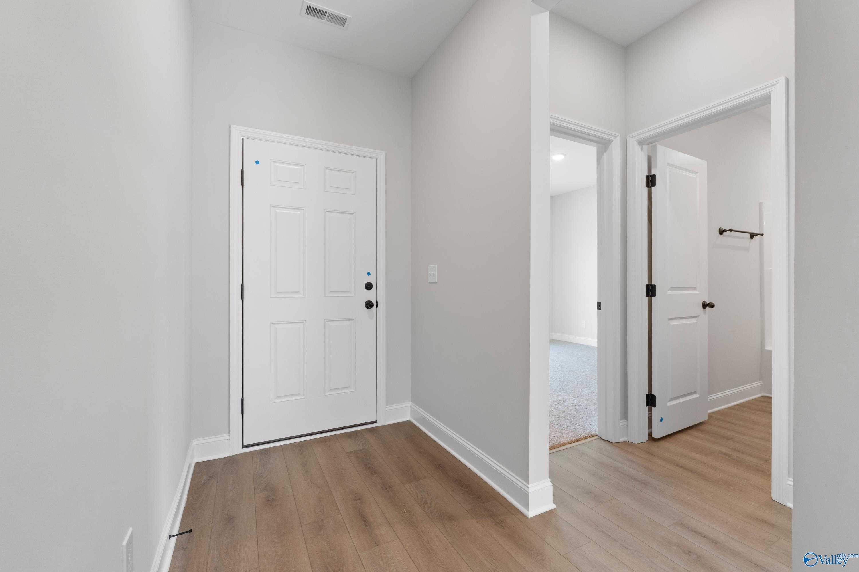 Bright hallway with gray walls, oak laminate floors, white doors to bedroom and bathroom in 3-bedroom Franklin C home, Hazel Green, AL
