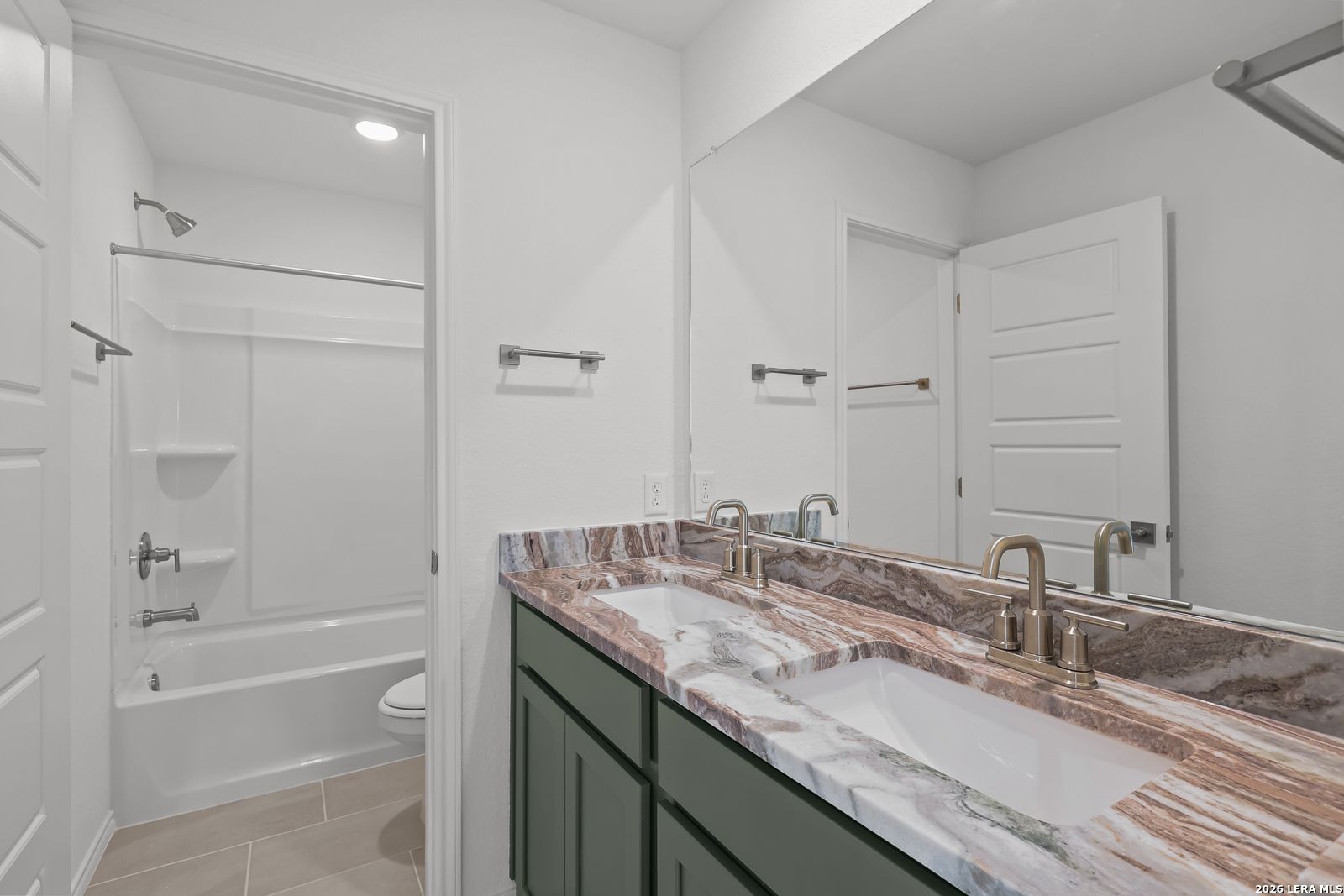 Modern bathroom with dual vanity, marble-style countertops, and shower-tub combo in The Brazos B home in Agave, San Antonio.