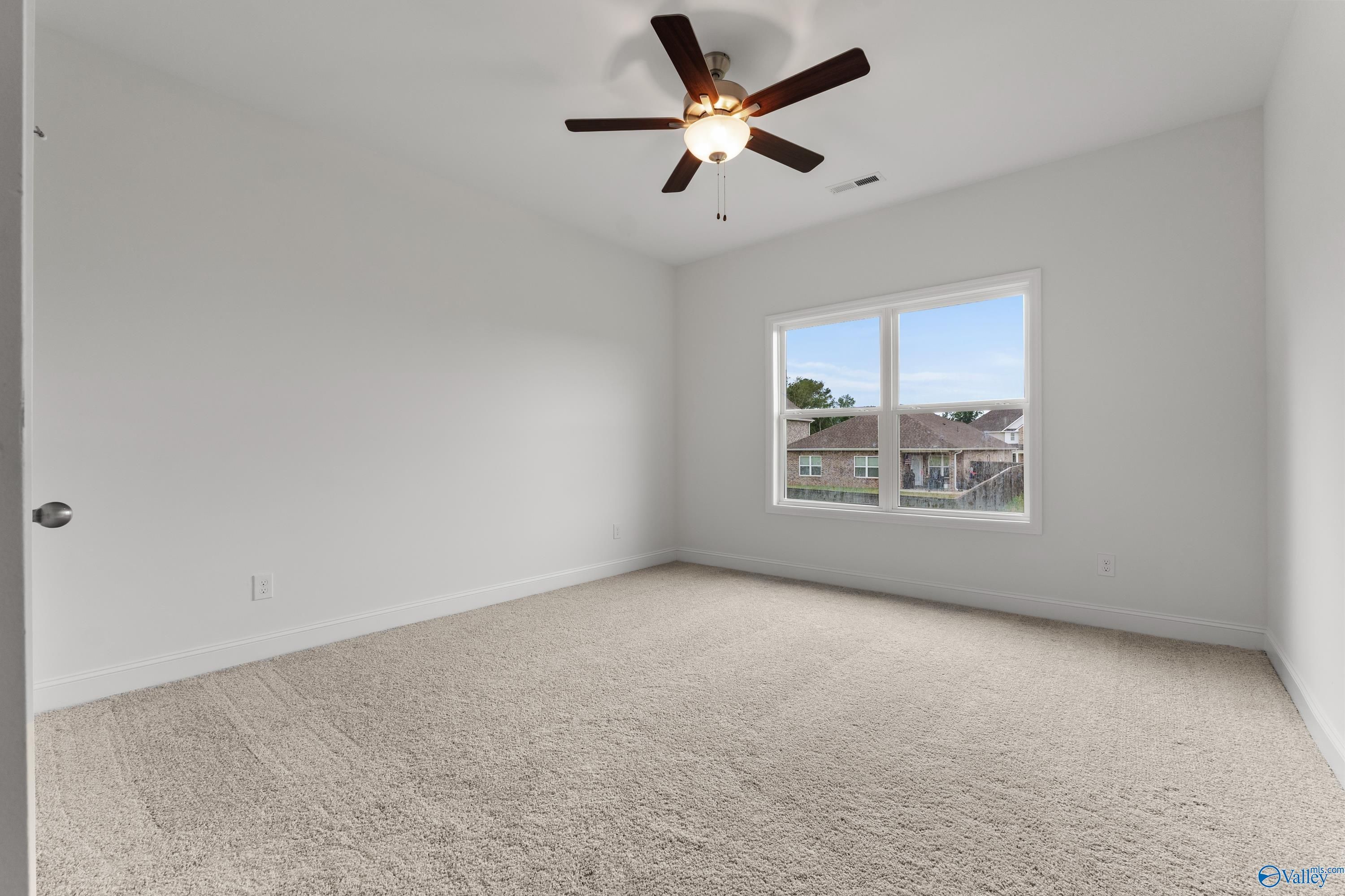 Bright secondary bedroom with ceiling fan, white walls, and large window overlooking neighborhood in Davidson Homes The Asheville C, New Market, Alabama