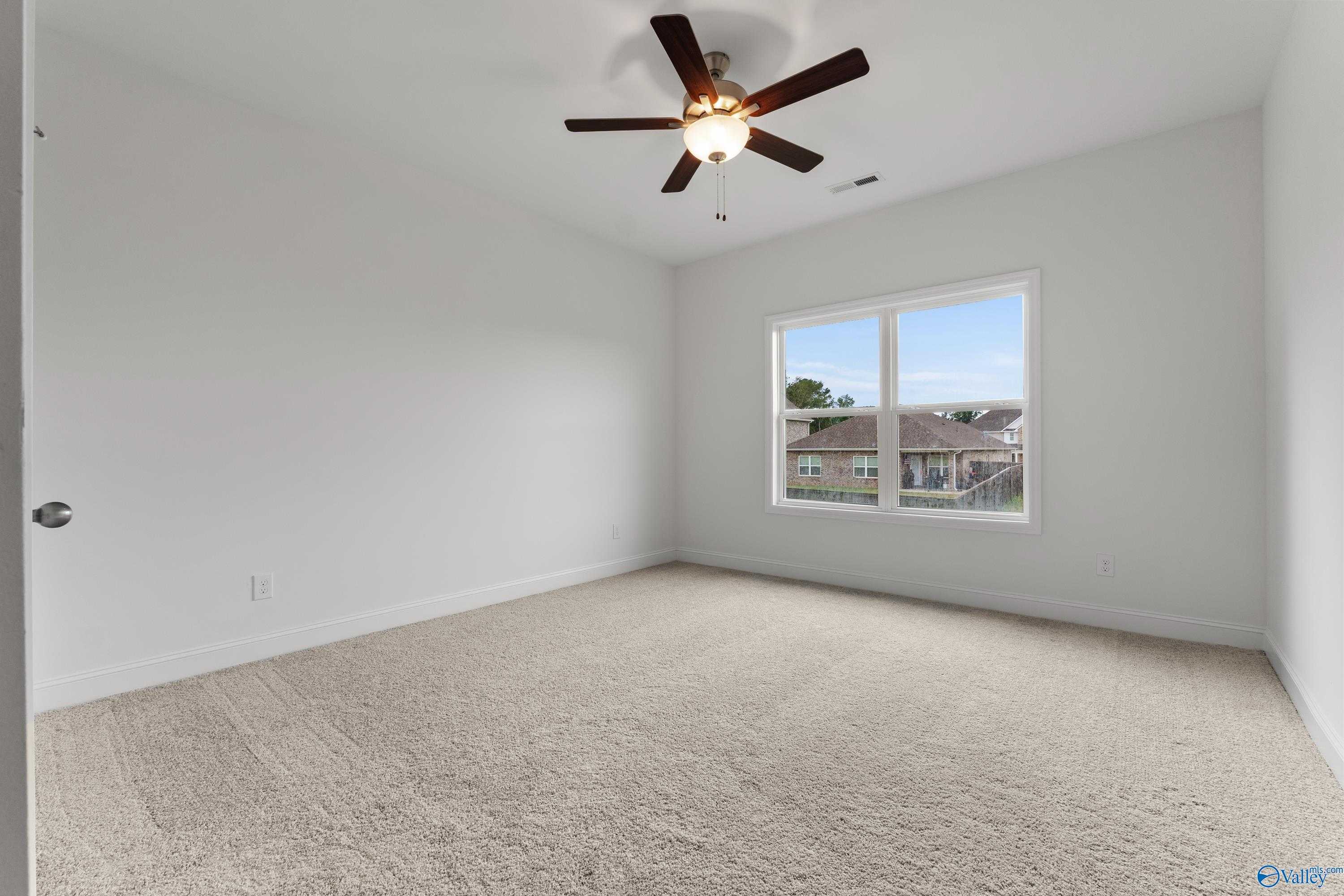 Bright secondary bedroom with ceiling fan, white walls, and large window overlooking neighborhood in Davidson Homes The Asheville C, New Market, Alabama