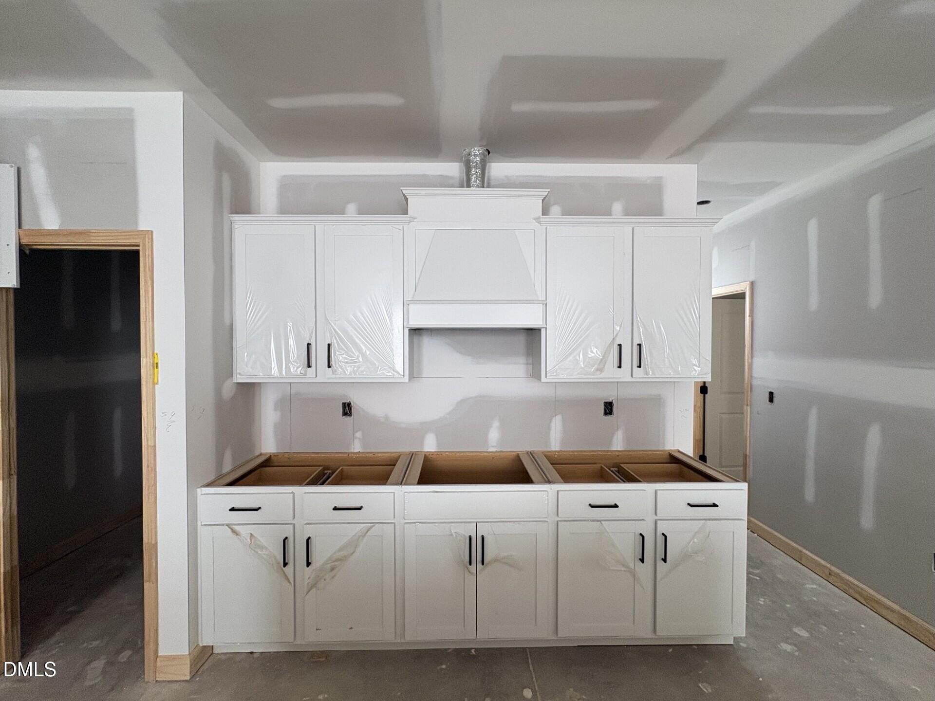 White kitchen cabinetry with range hood installed in new construction Adalynn A floor plan at Woodland Crossing, Zebulon.