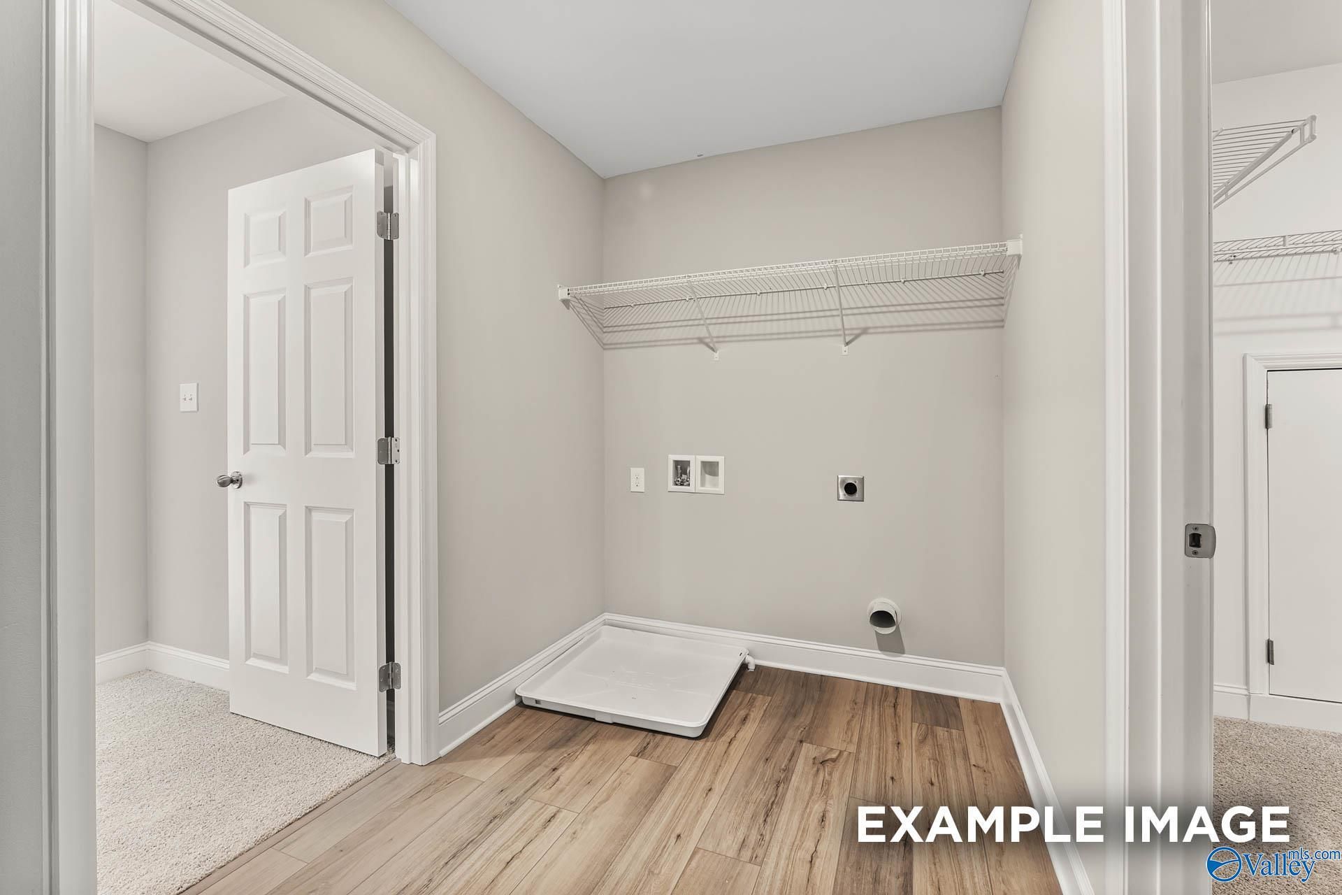 Spacious laundry room with wire shelving, washer/dryer hookups, utility sink and hardwood floors in Davidson Homes Chelsea B, Toney AL