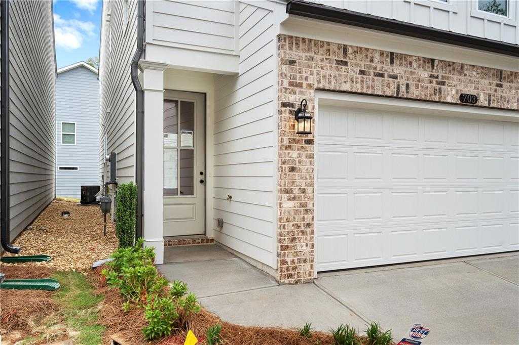 Modern two-story home facade with white siding, brick accents, two-car garage, and front landscaping in The Village at Shallowford, Kennesaw, Georgia